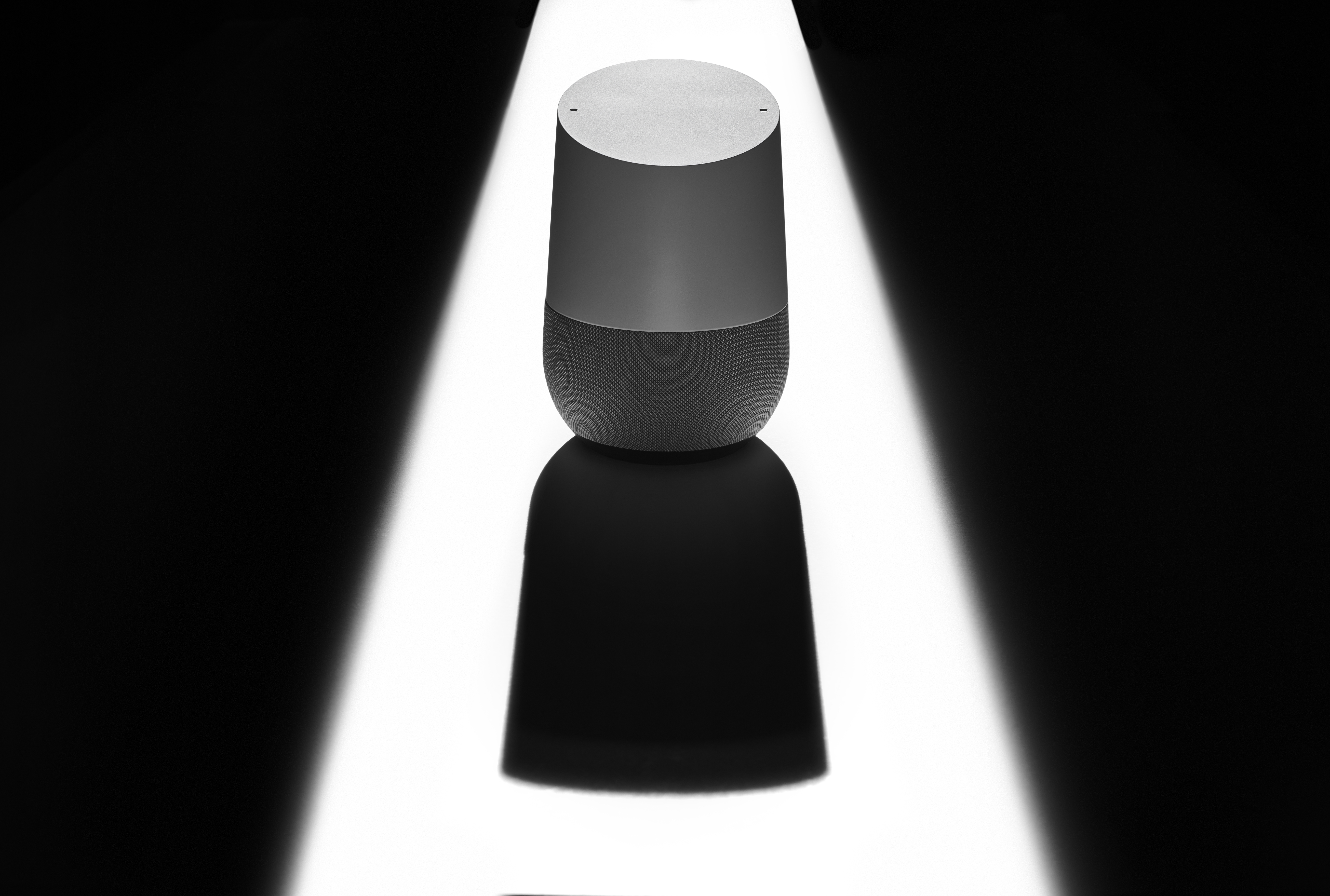A Google Home smart speaker casting a sinister shadow, to represent issues of privacy and security.