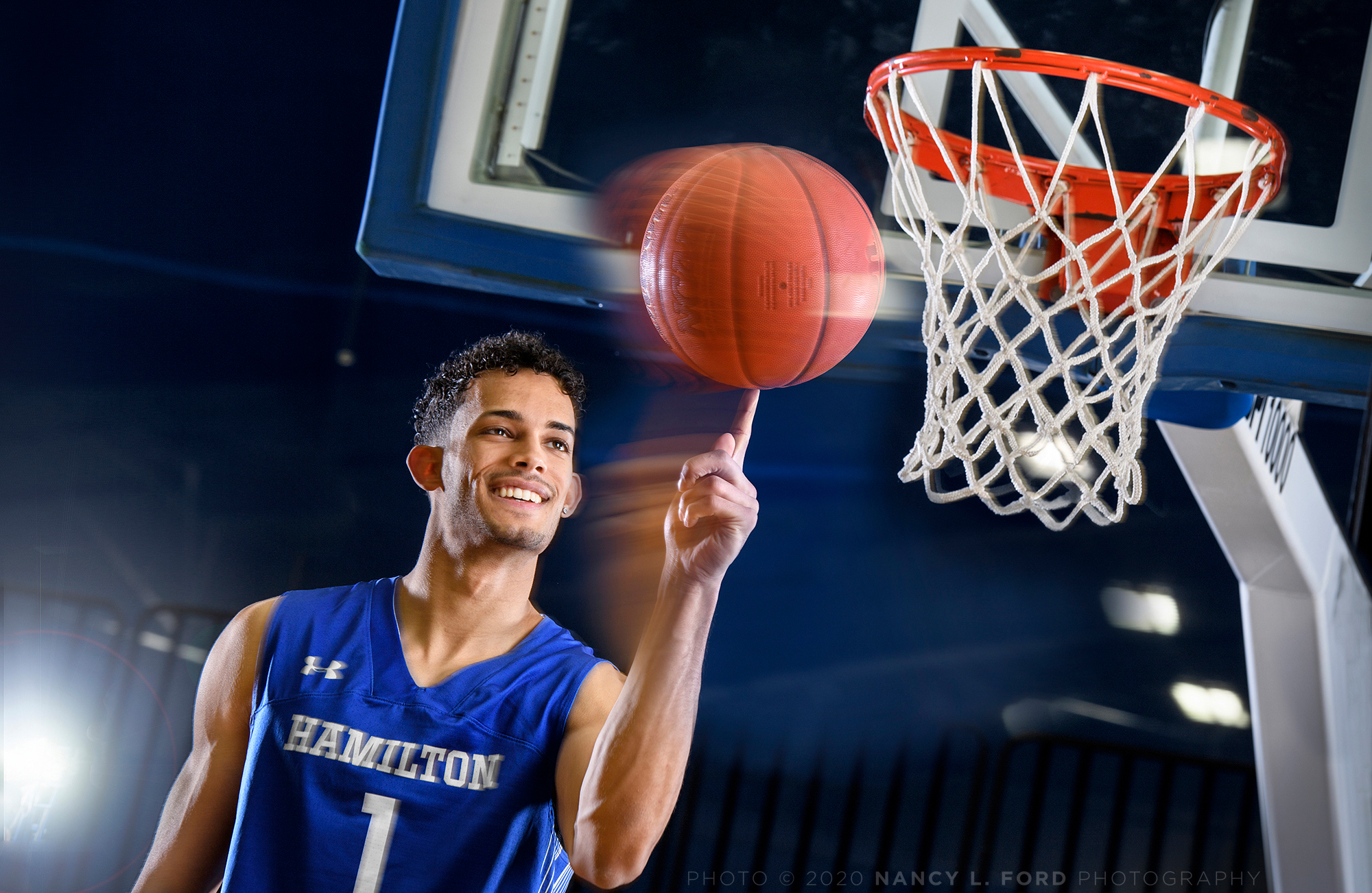 Kena Gilmour spins a basketball on his finger under a basket