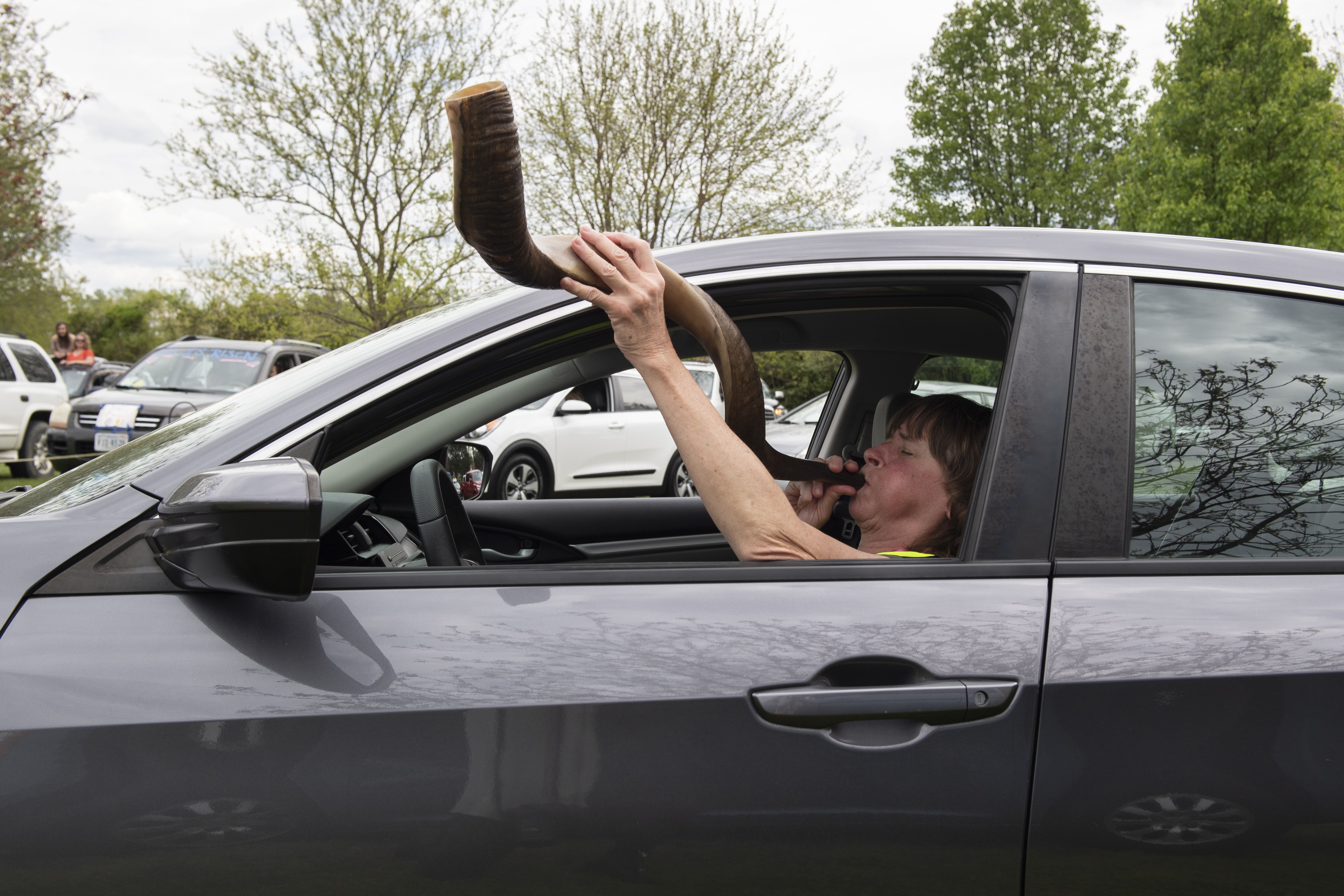 A woman in a car blowing a shofar.