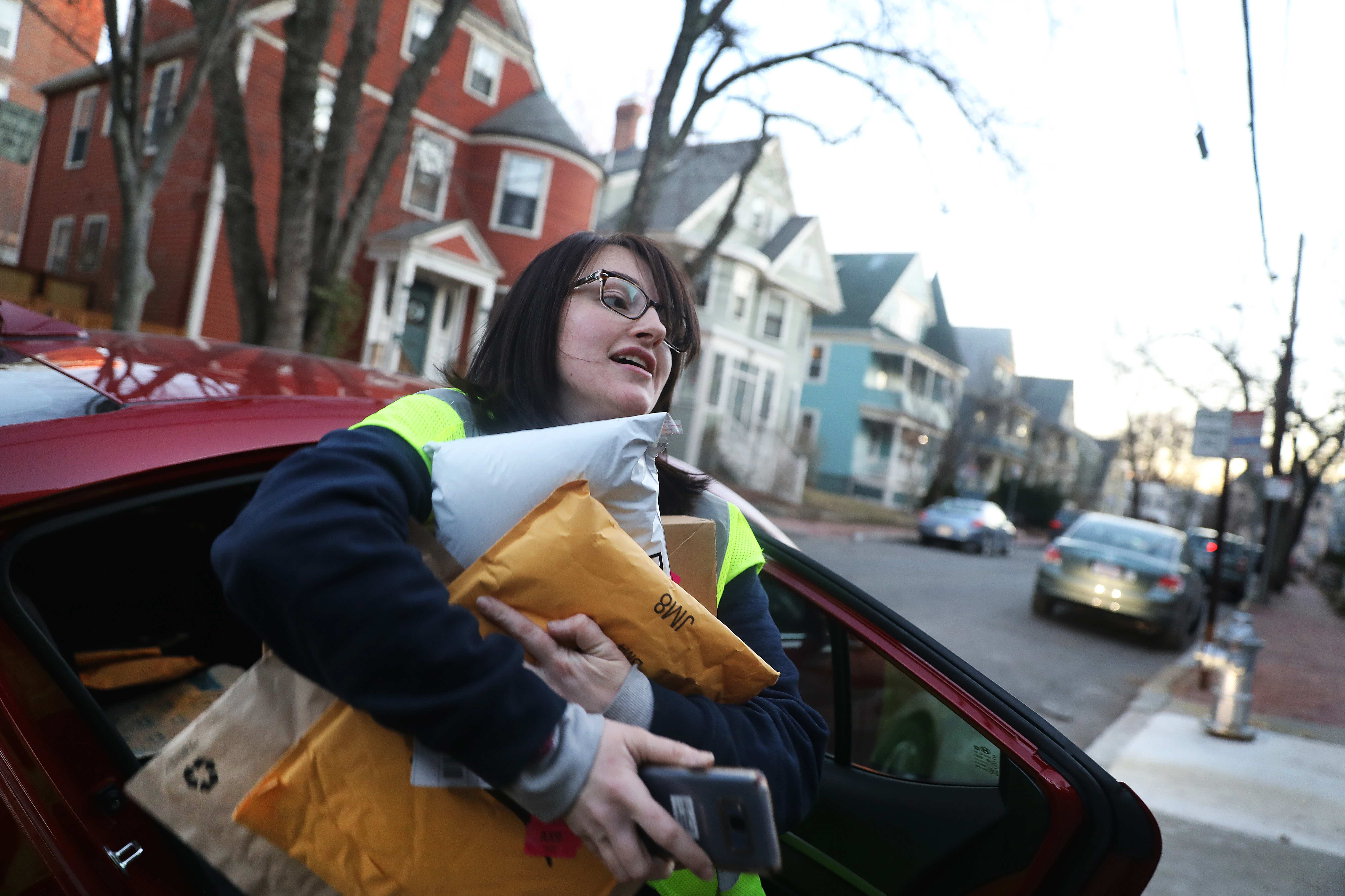 A woman gets out of her car with her arms full of packages.