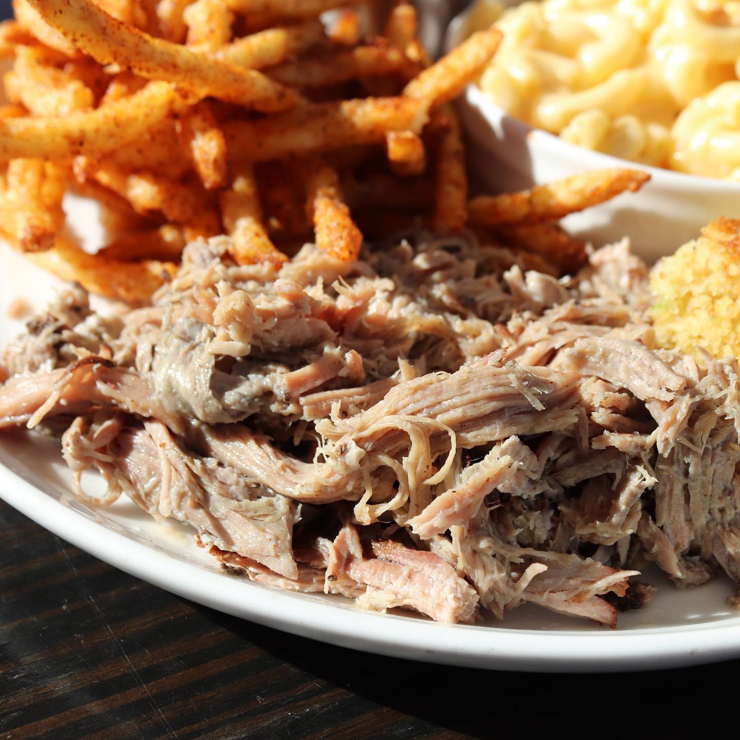 A plate of pulled pork with a side of seasoned fries and cornbread from Texican Barbecue in Roswell, GA