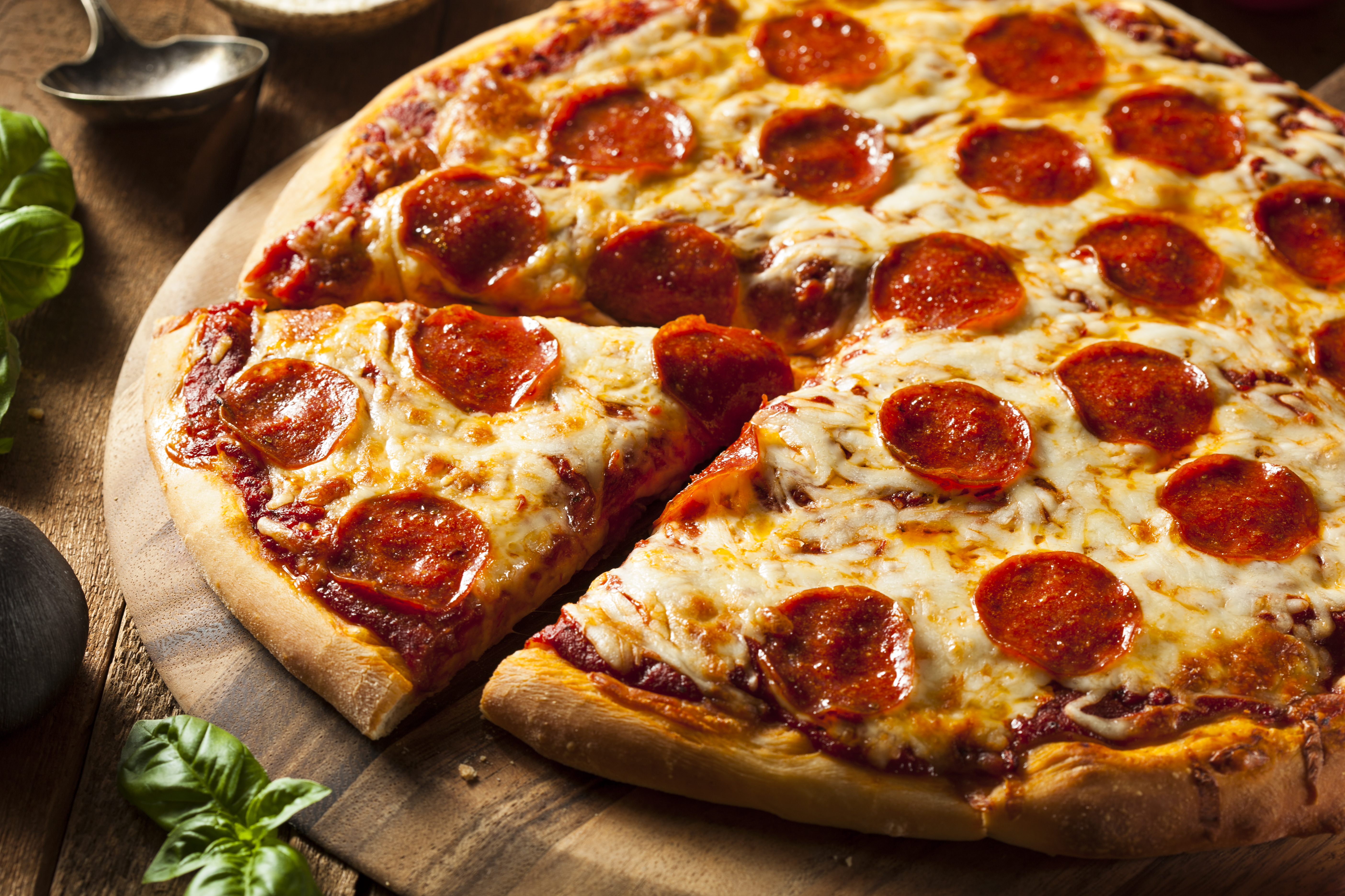 一份切了一片的意大利辣香肠披萨，放在木板上