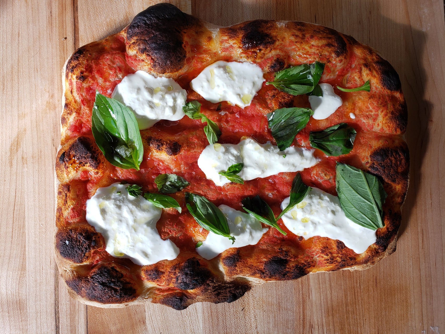The namesake Stracci pizza has fresh stracciatella cheese, tomato, basil, and olive oil