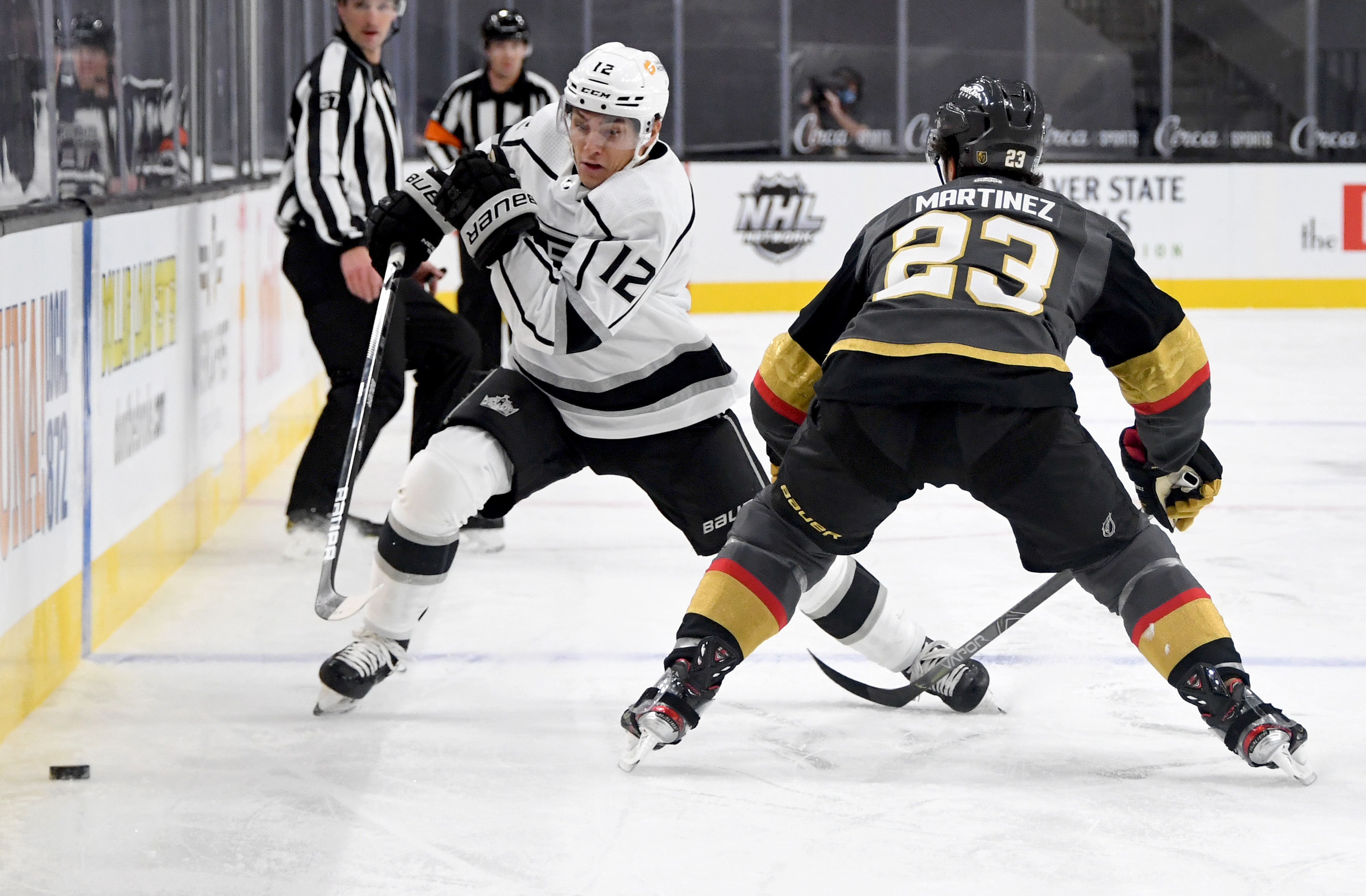 Trevor Moore #12 of the Los Angeles Kings tries to skate past Alec Martinez #23 of the Vegas Golden Knights in the first period of their game at T-Mobile Arena on February 5, 2021 in Las Vegas, Nevada. The Golden Knights defeated the Kings 5-2.
