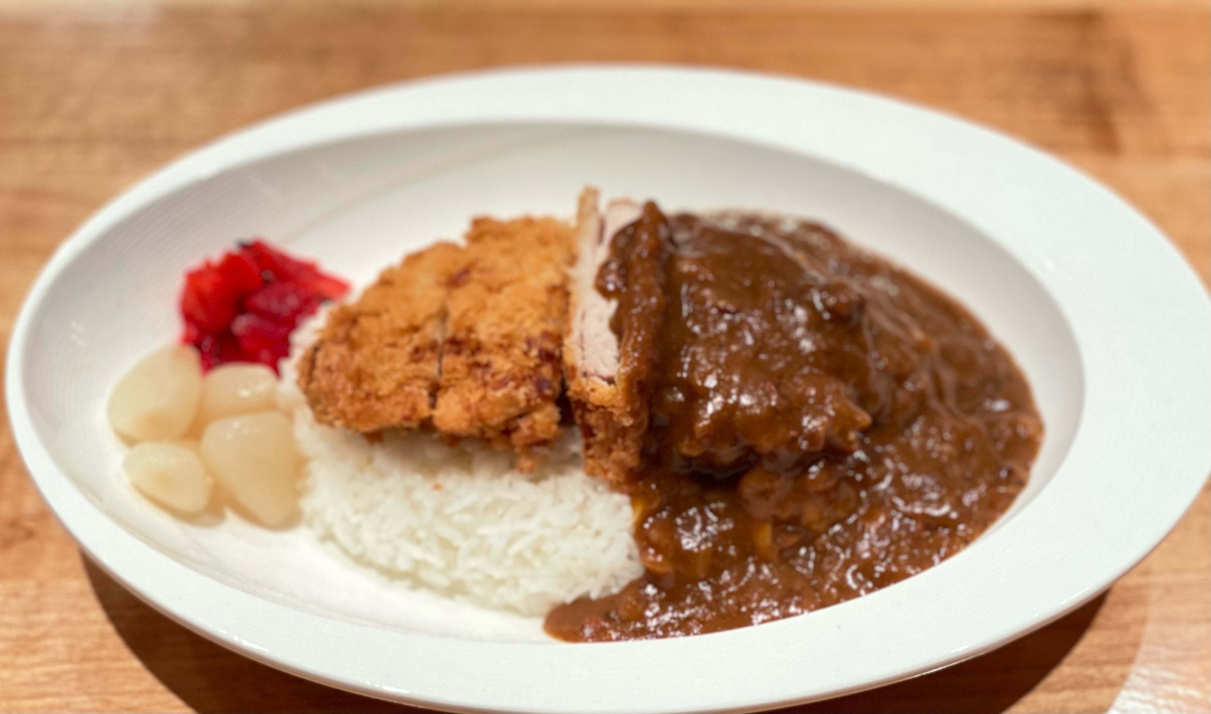 A plate of katsu curry: Crispy breaded fried pork on the left; dark, rich beef-based curry gravy on the right