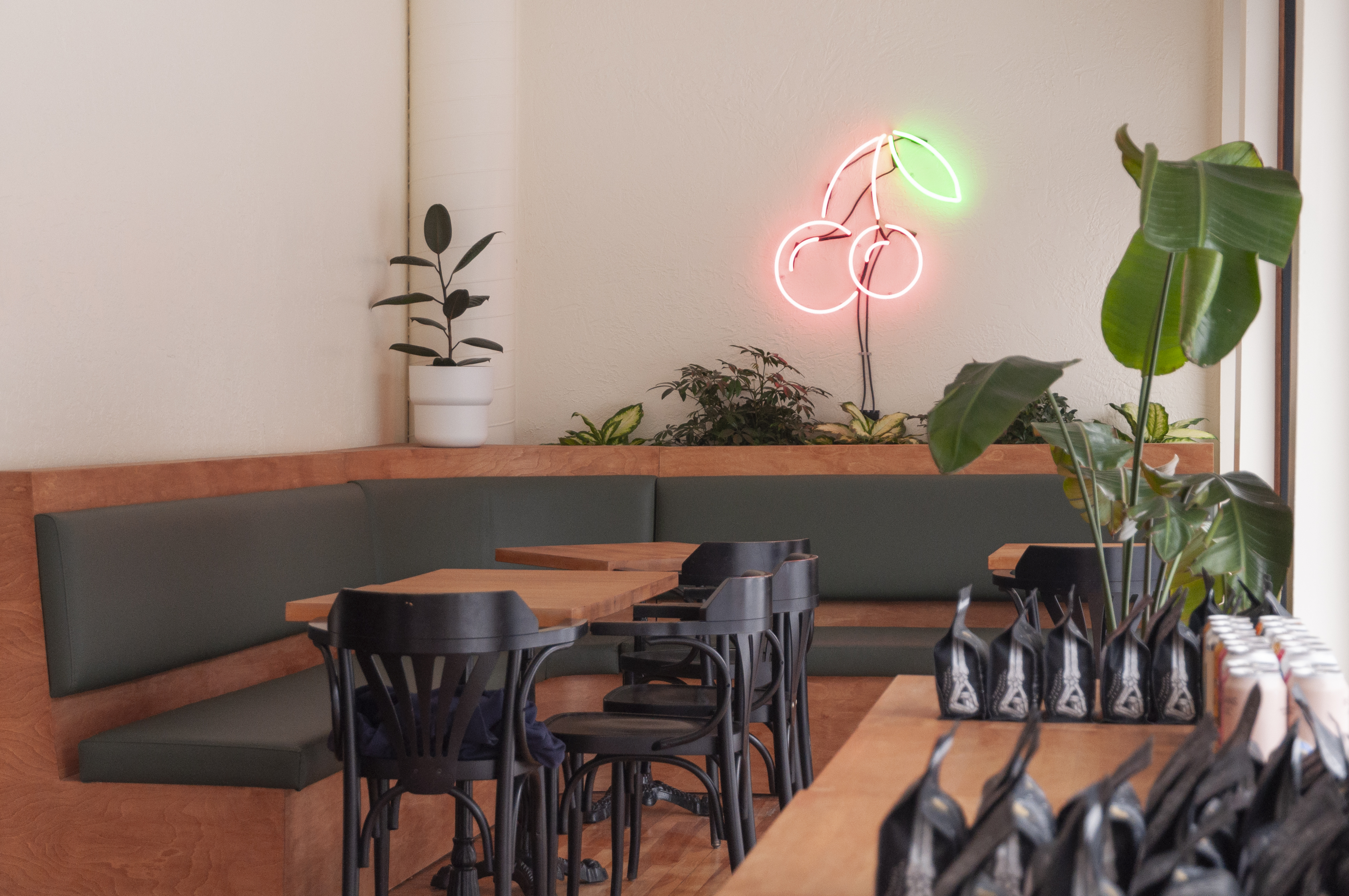 empty café with wood tables and black chairs and cherry neon sign
