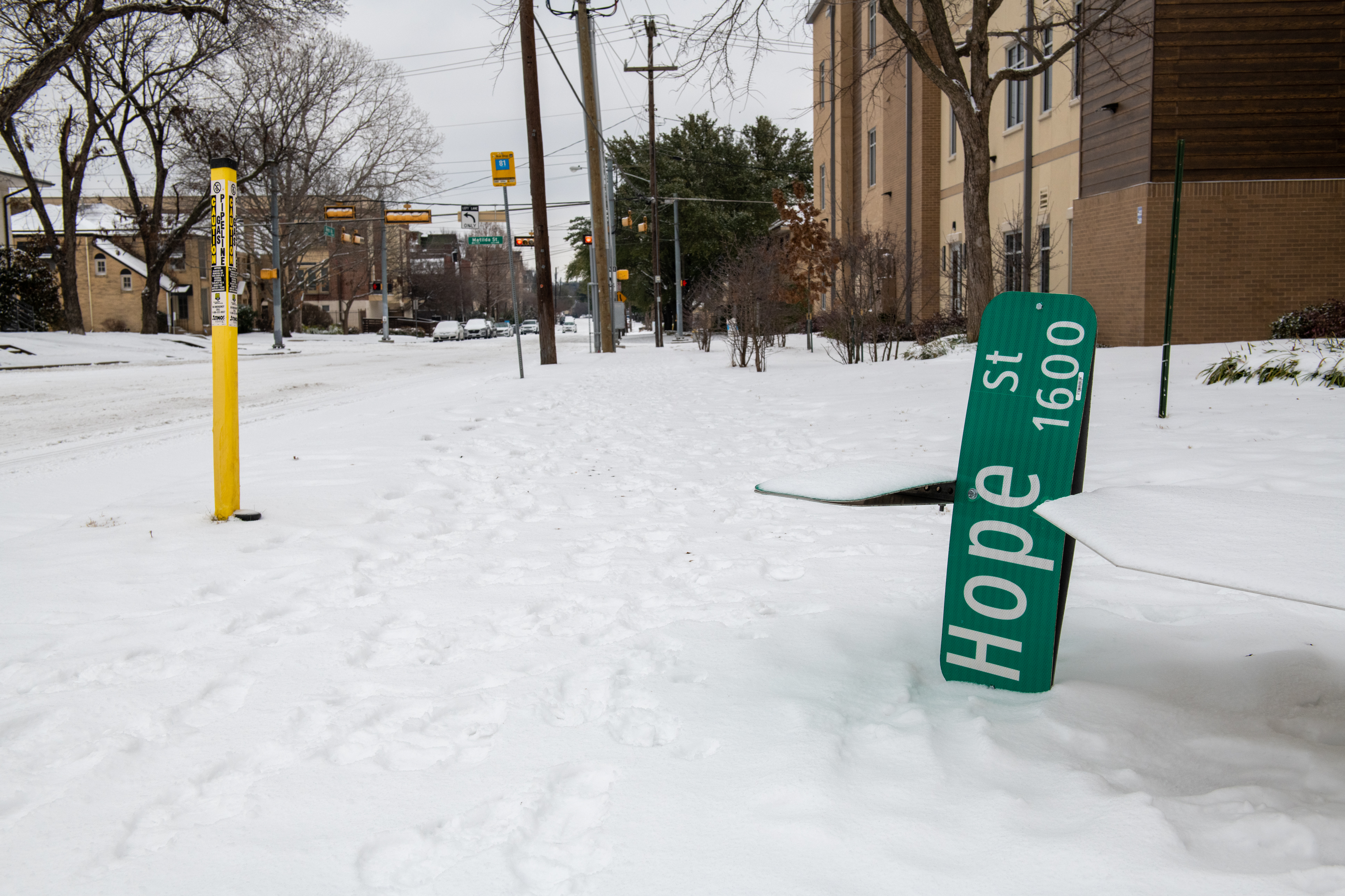 An overturned street sign that reads “Hope Street” laying on a snow-covered street 