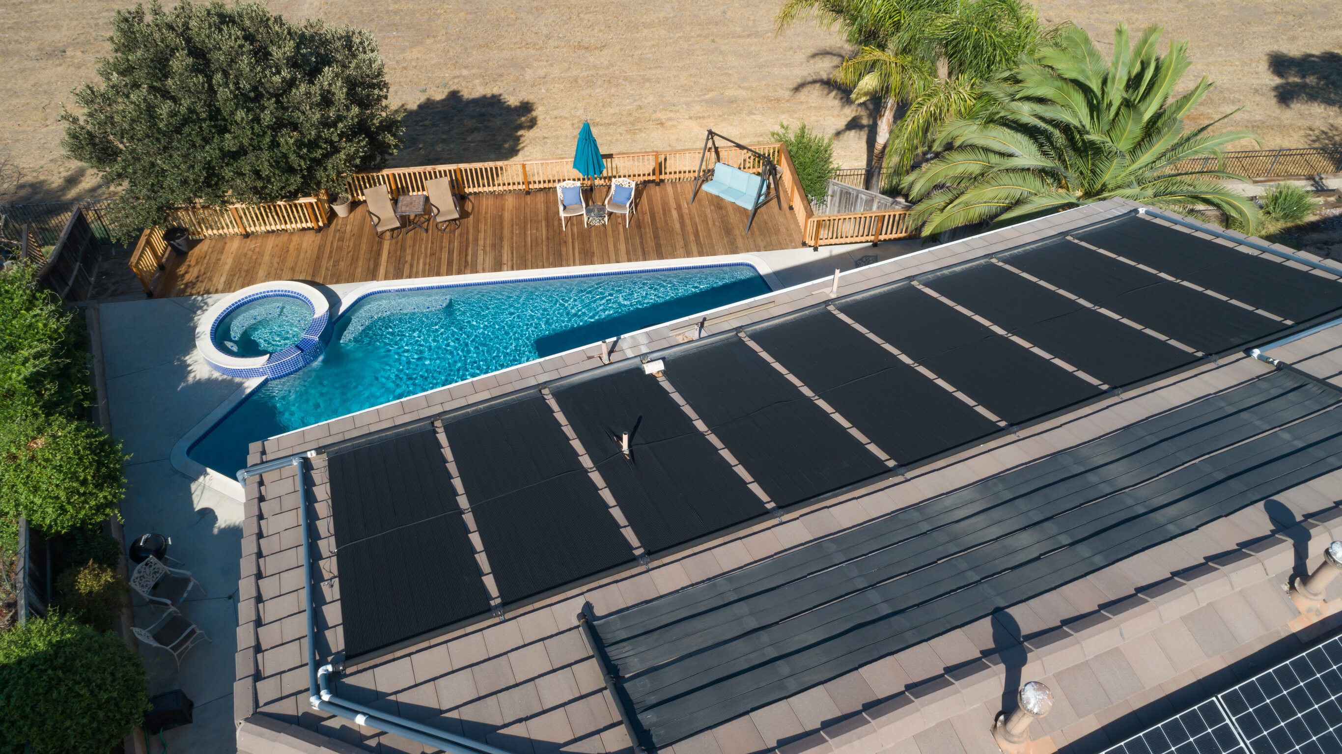 Solar panels on the roof of a home overlooking a pool in the backyard. 