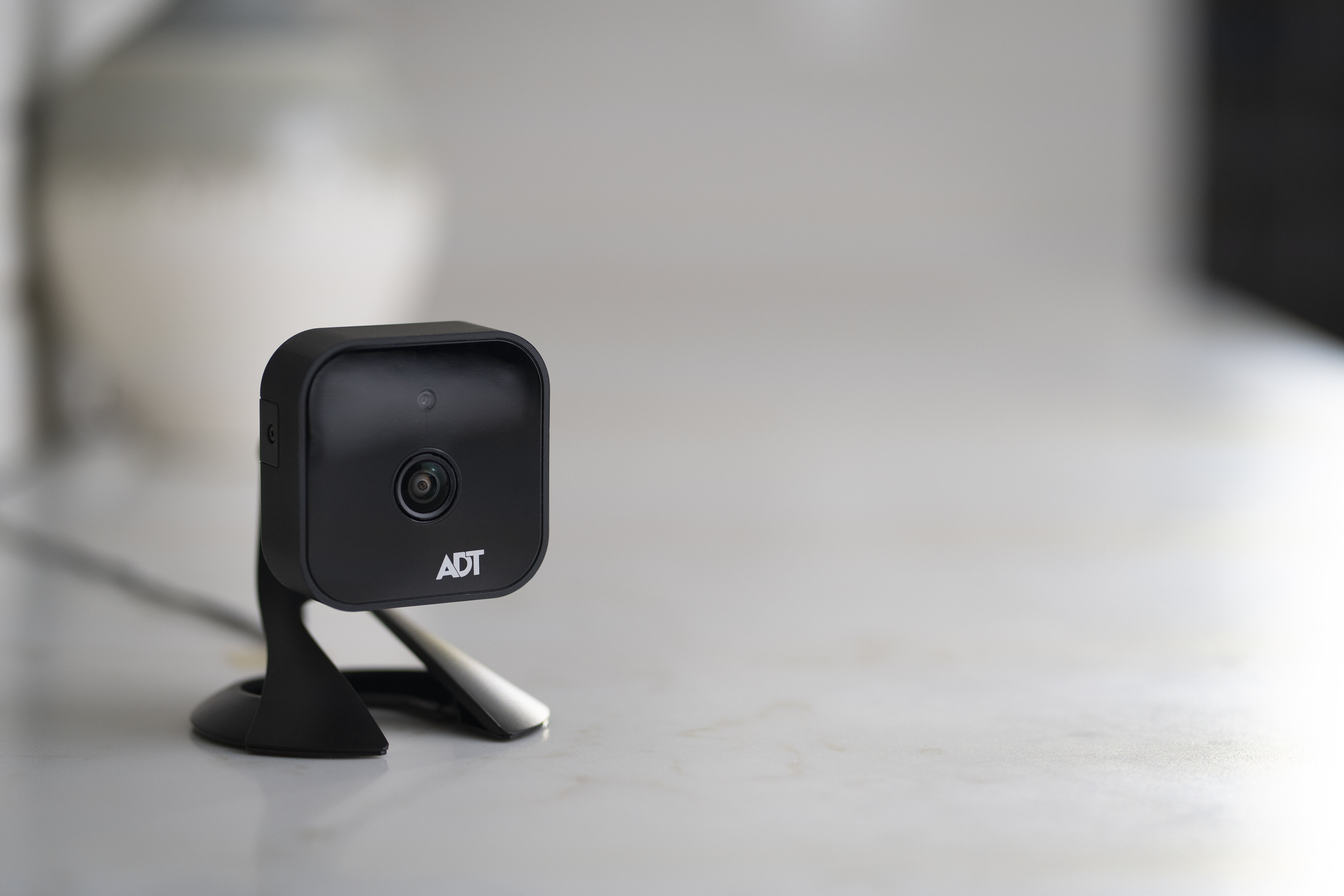 An ADT security camera sits on a gray countertop in a home
