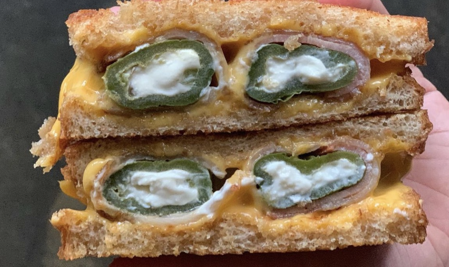 A cross-section of a bacon-wrapped jalapeño popper grilled cheese sandwich