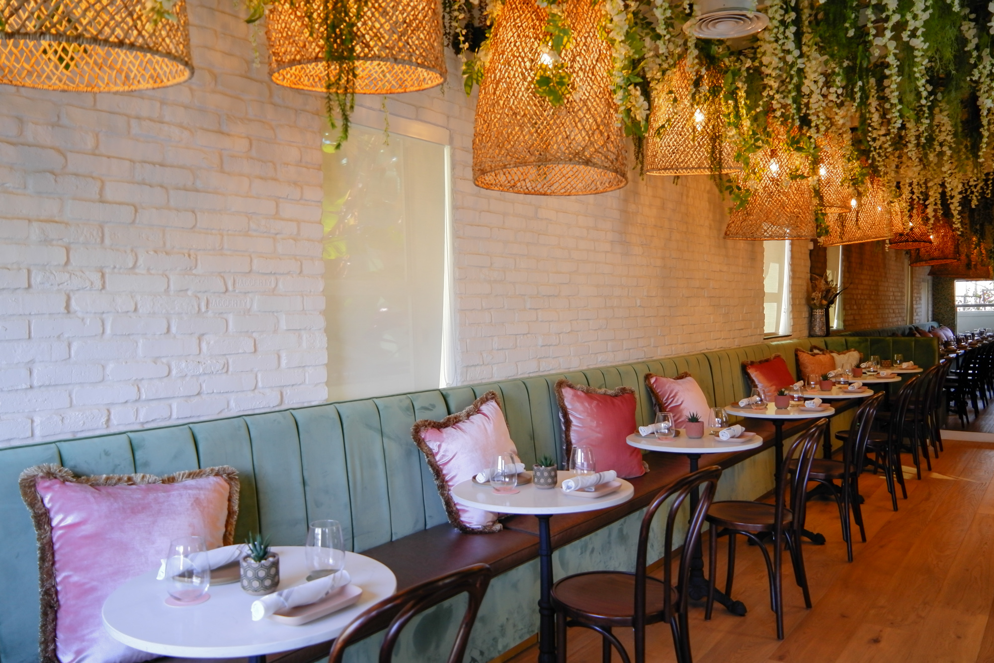 banquettes of green with pink pillows and hanging lamps