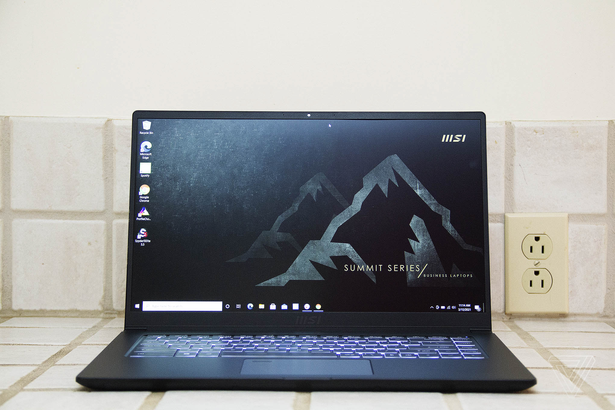 The MSI Summit B15 sits on a tiled countertop, open. The screen displays white mountains on a black background with the MSI and Summit logos.