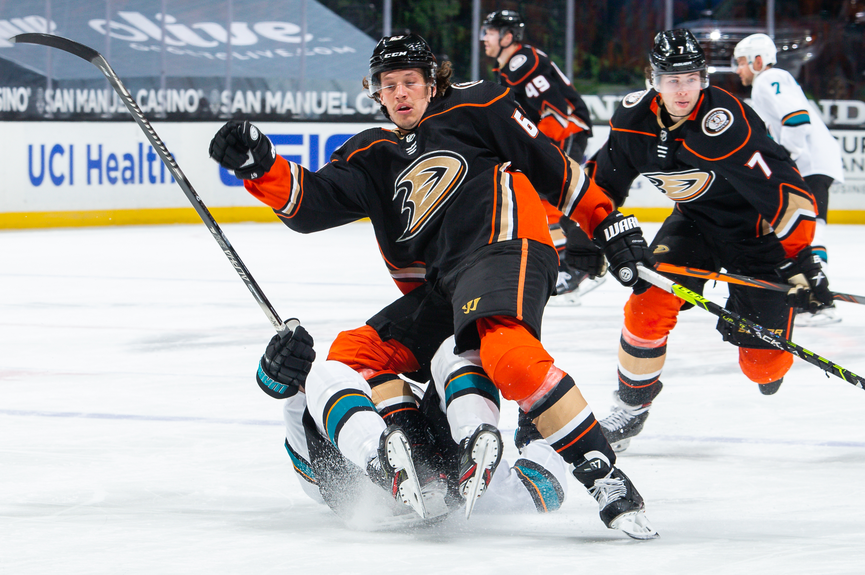 Rickard Rakell #67 of the Anaheim Ducks collides with Ryan Donato #16 of the San Jose Sharks as Ben Hutton #7 of the Anaheim Ducks skates past during the third period of the game at Honda Center on March 12, 2021 in Anaheim, California.