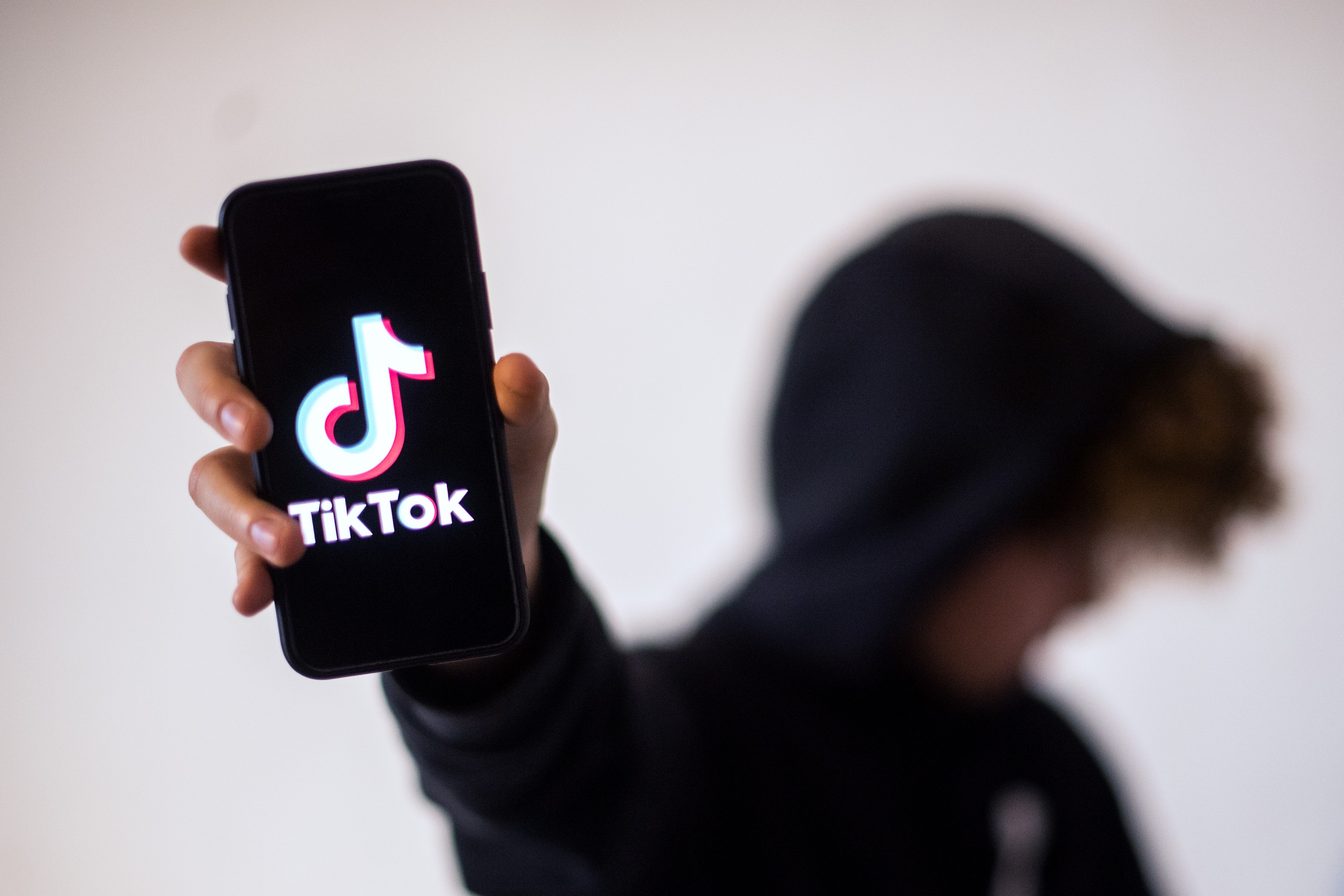 A person in a hoodie holds up a smartphone with the logo of Chinese social network TikTok, on January 21, 2021, in Nantes, western France.