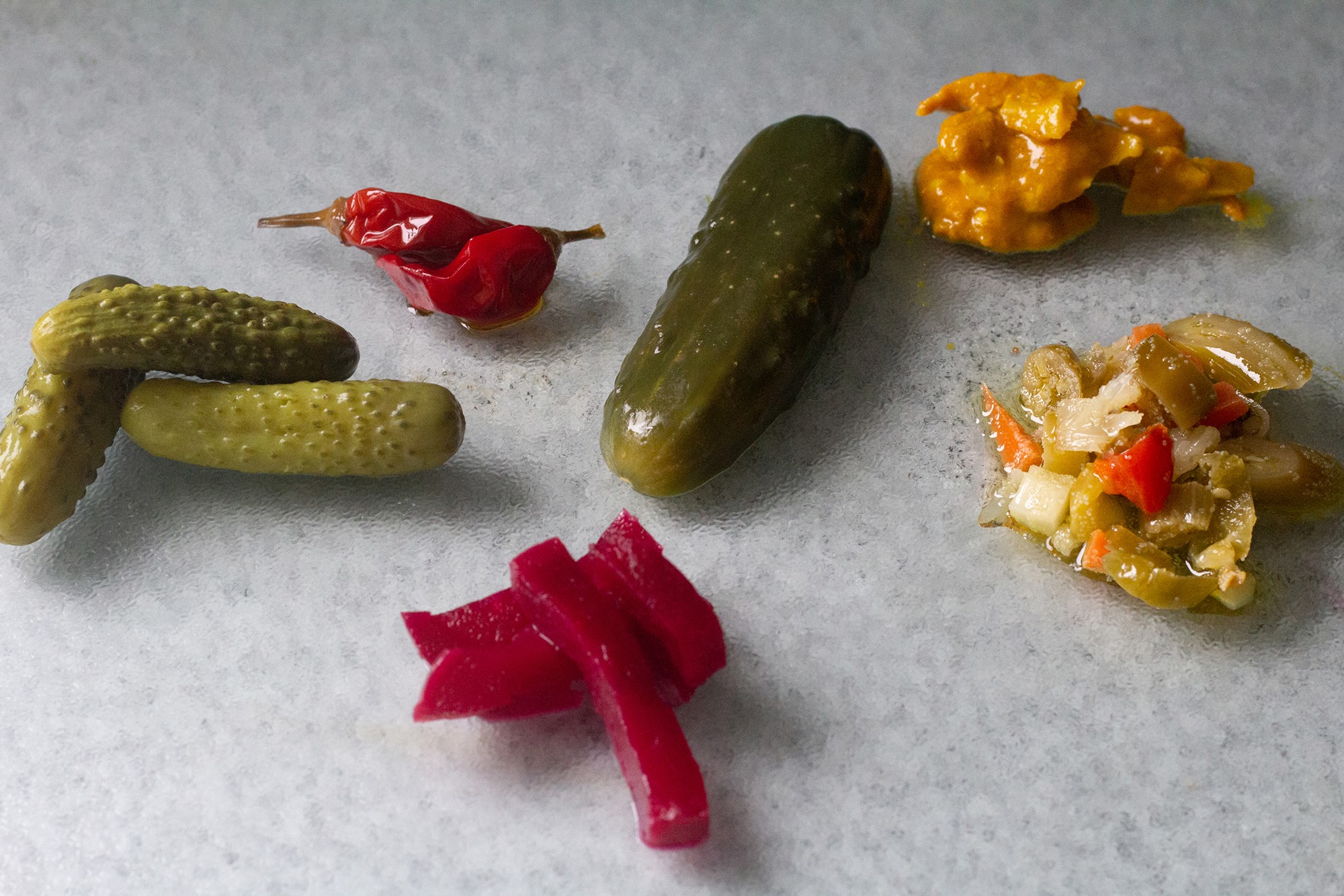 A spread of pickled vegetables laid out on a slate counter