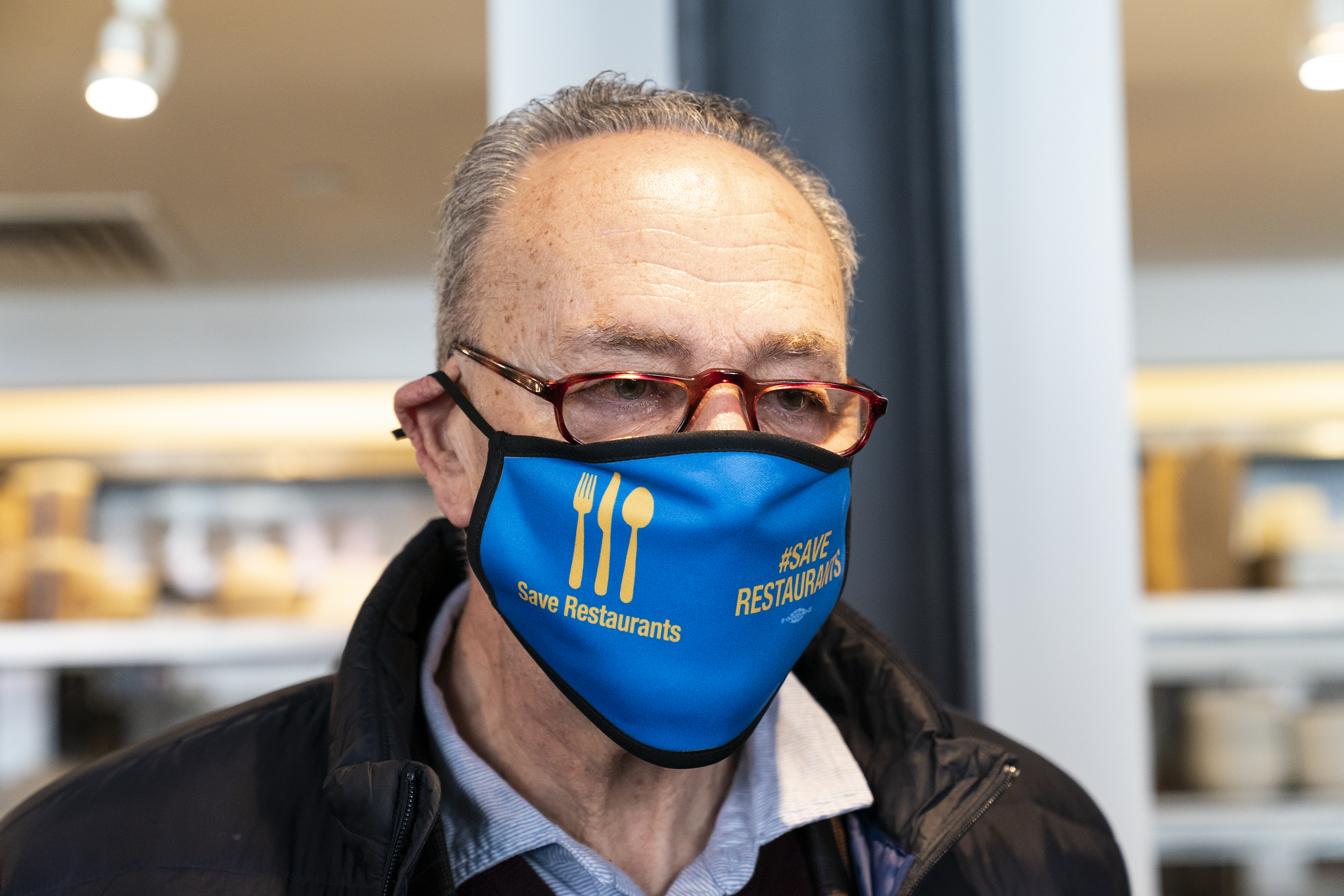 参议院多数党领袖查克·舒默戴着一个面具，上面写着“……