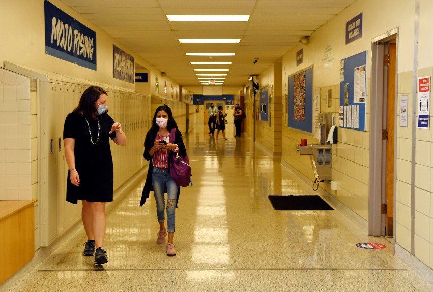 A teacher walks next to a student in a middle school hallway.