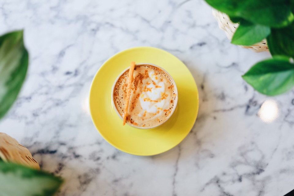 A yellow mug holds a coffee drink