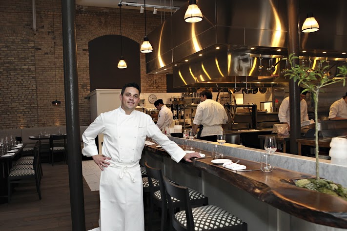 Gavin Kaysen leans on the bar seating in front of the open kitchen at Spoon and Stable