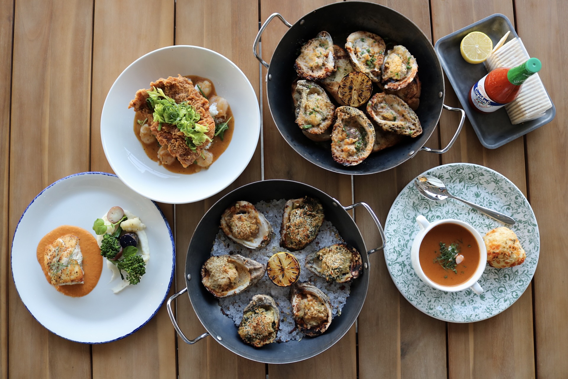Oysters, seafood bisque, and other seafood dishes on a wood table