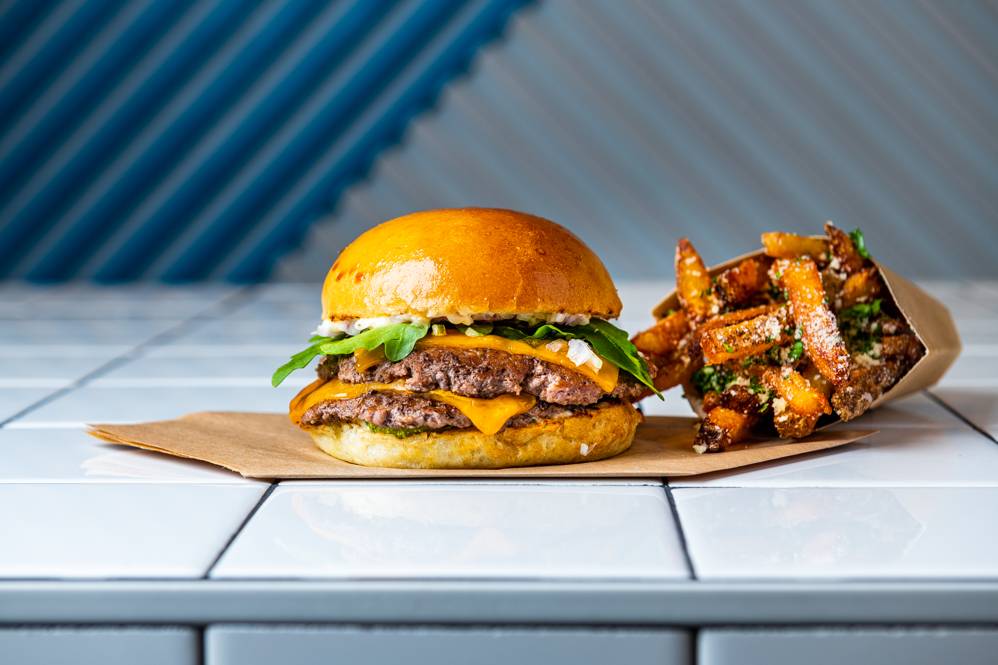 A beef burger patty with arugula, dill pickle, stack sauce, and Parmesan truffle fries.