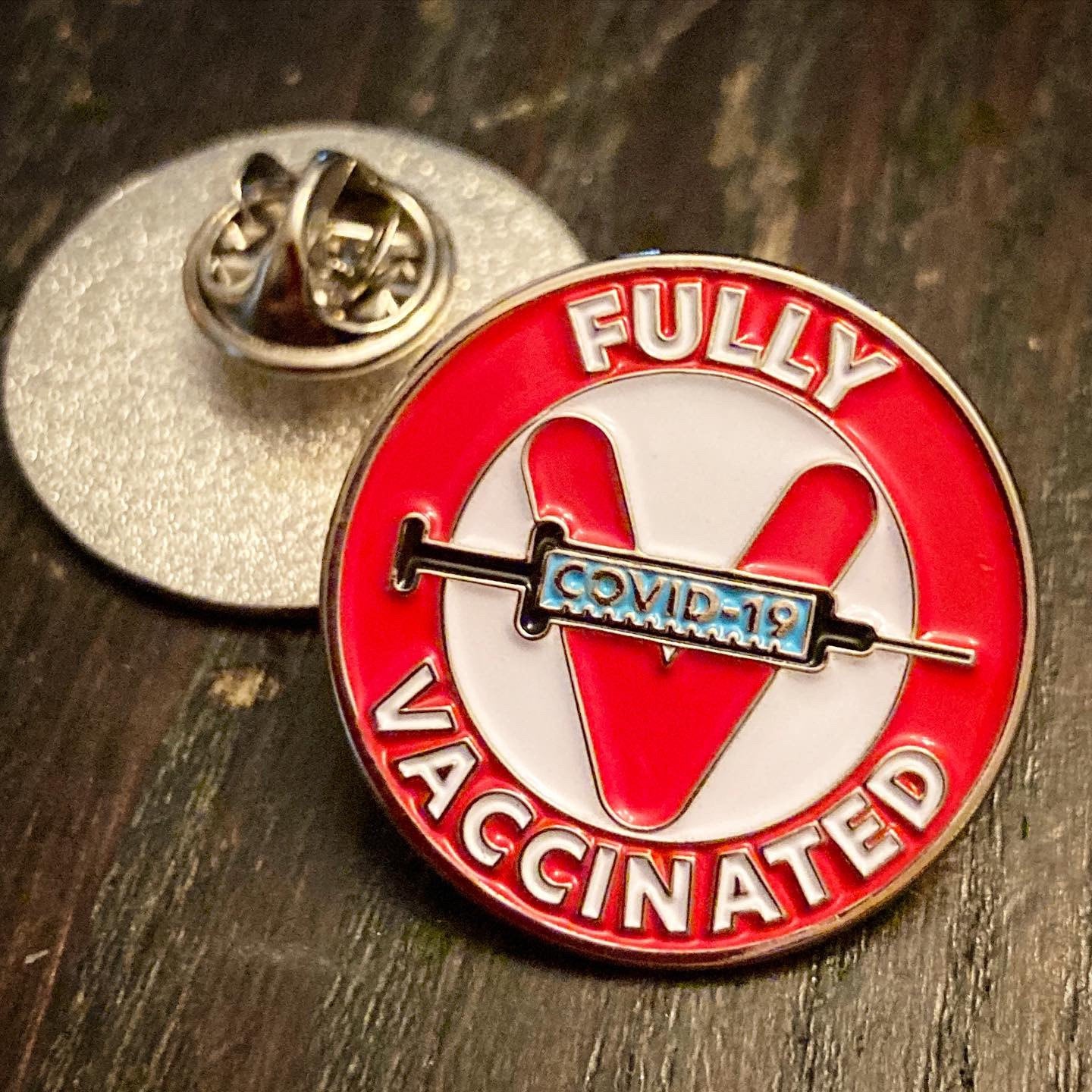 A metal pin that says “Fully vaccinated” and has a syringe that reads “Covid-19.”