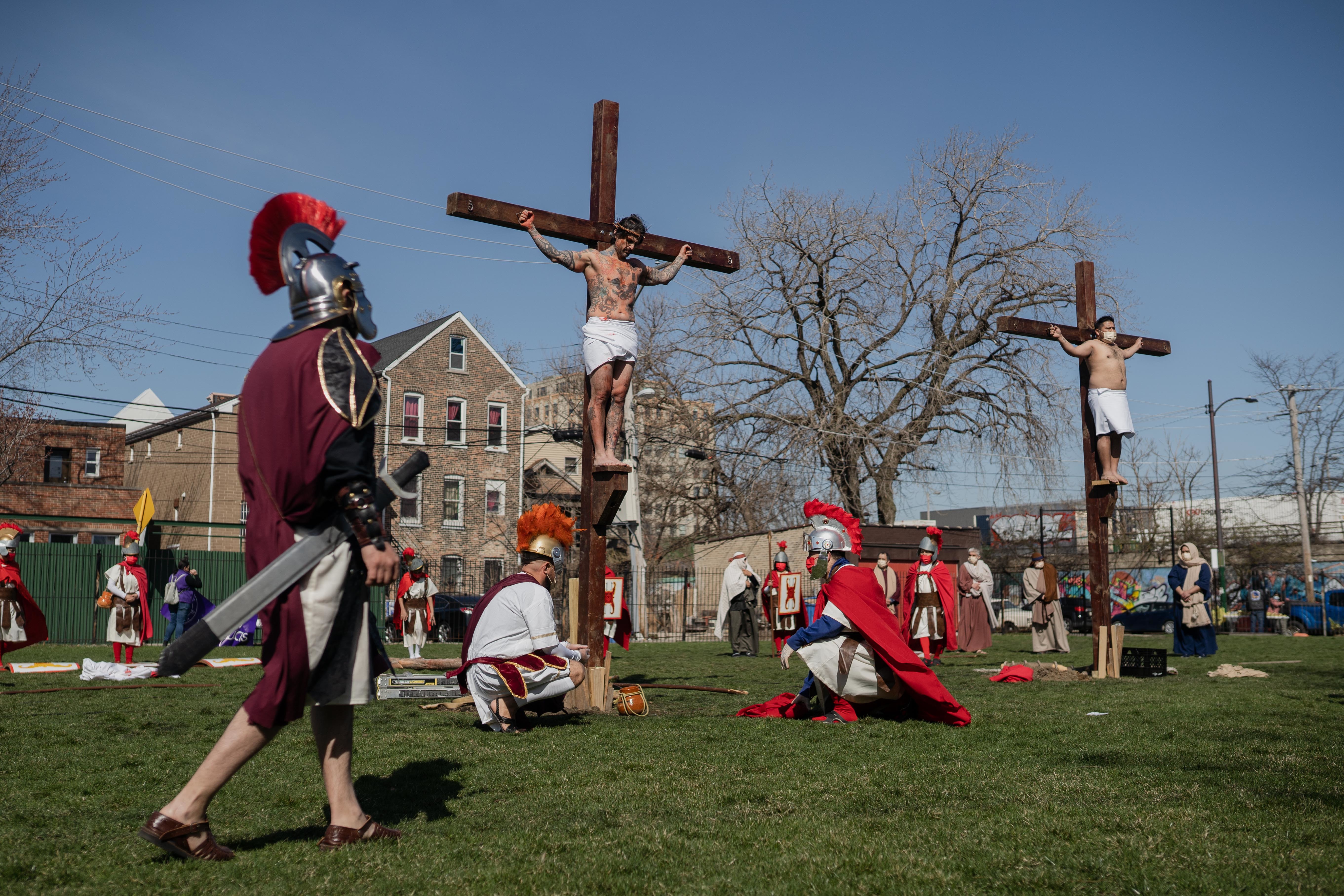 Isaac Bucio, who plays Jesus Christ, acts as if he is crucified during Via Crucis on the field of St. Procopius Catholic Church in Pilsen, Friday morning, April 2, 2021. The annual Via Crucis is a Good Friday tradition that reenacts the Stations of the Cross, a Catholic devotion that recounts Jesus’ passion and death.