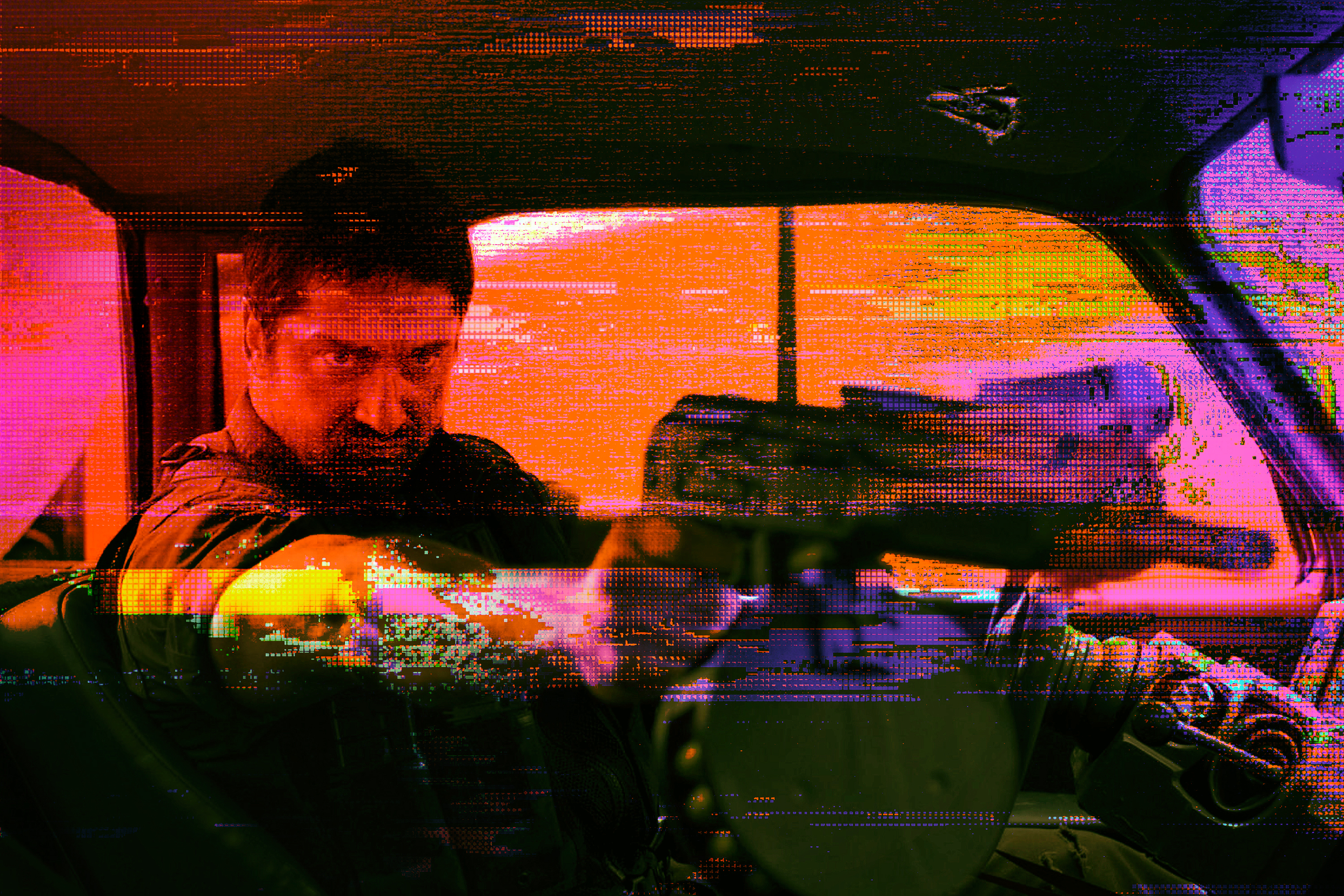 Glitchy, brightly colored image of actor Gerard Butler pointing a large gun in Gamer