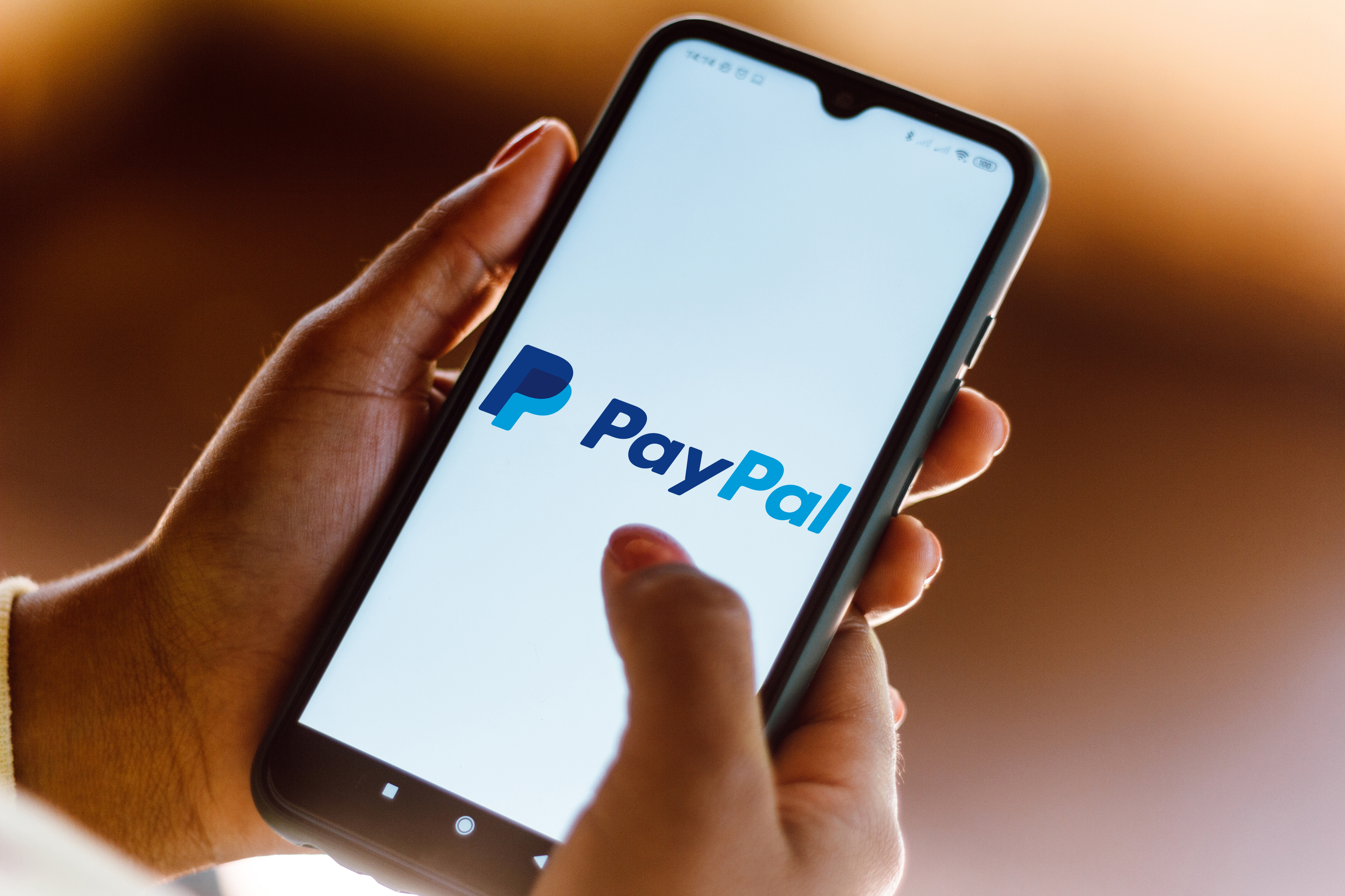 A person opening the PayPal app on their phone