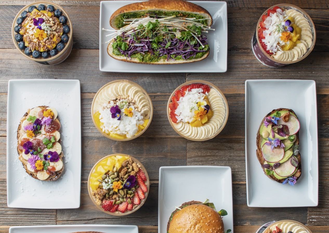 A top-down view of colorful acai bowls, sandwiches, and burgers from Plantiful in Kirkland, Washington