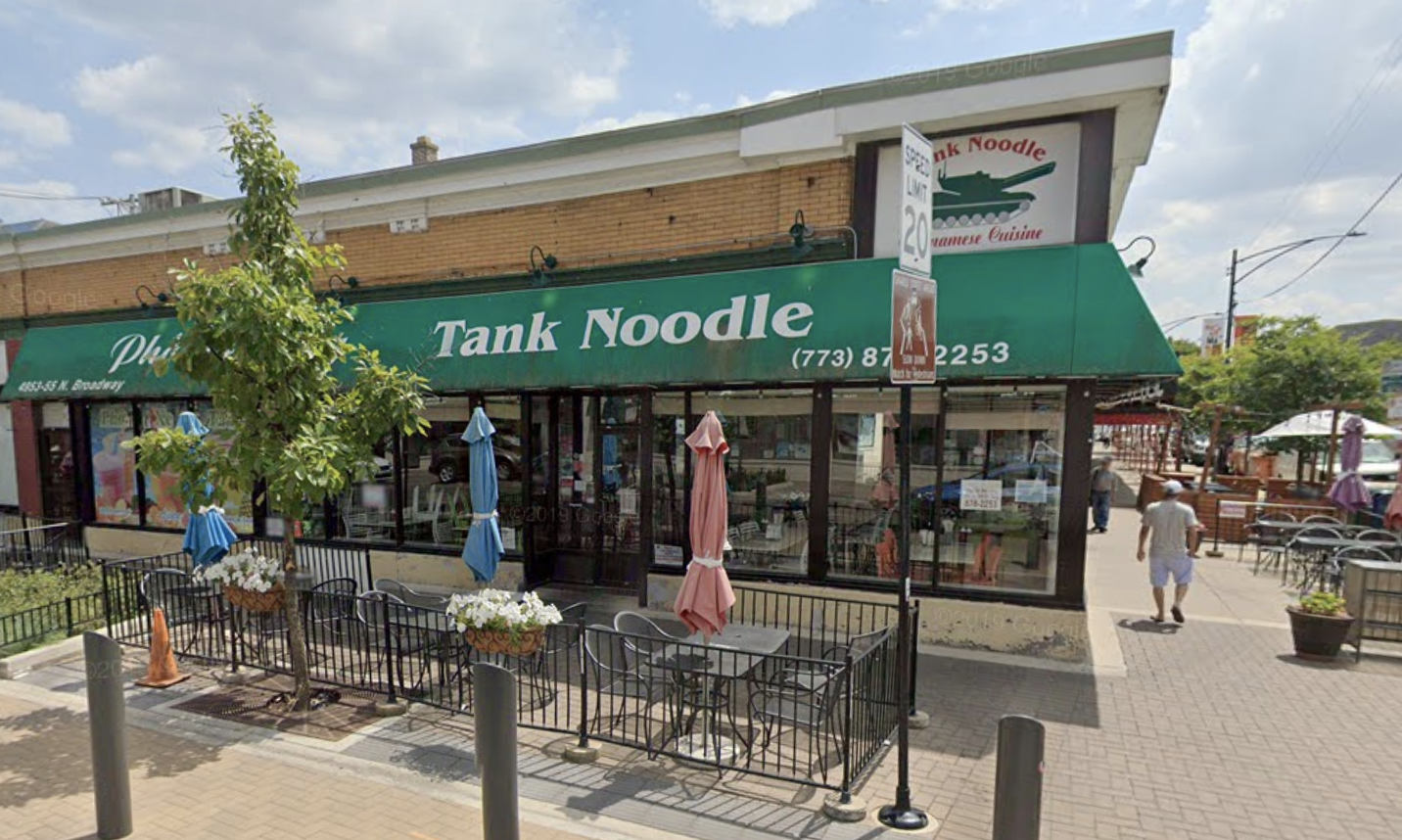 A corner restaurant with green awning that reads “Tank Noodle.”