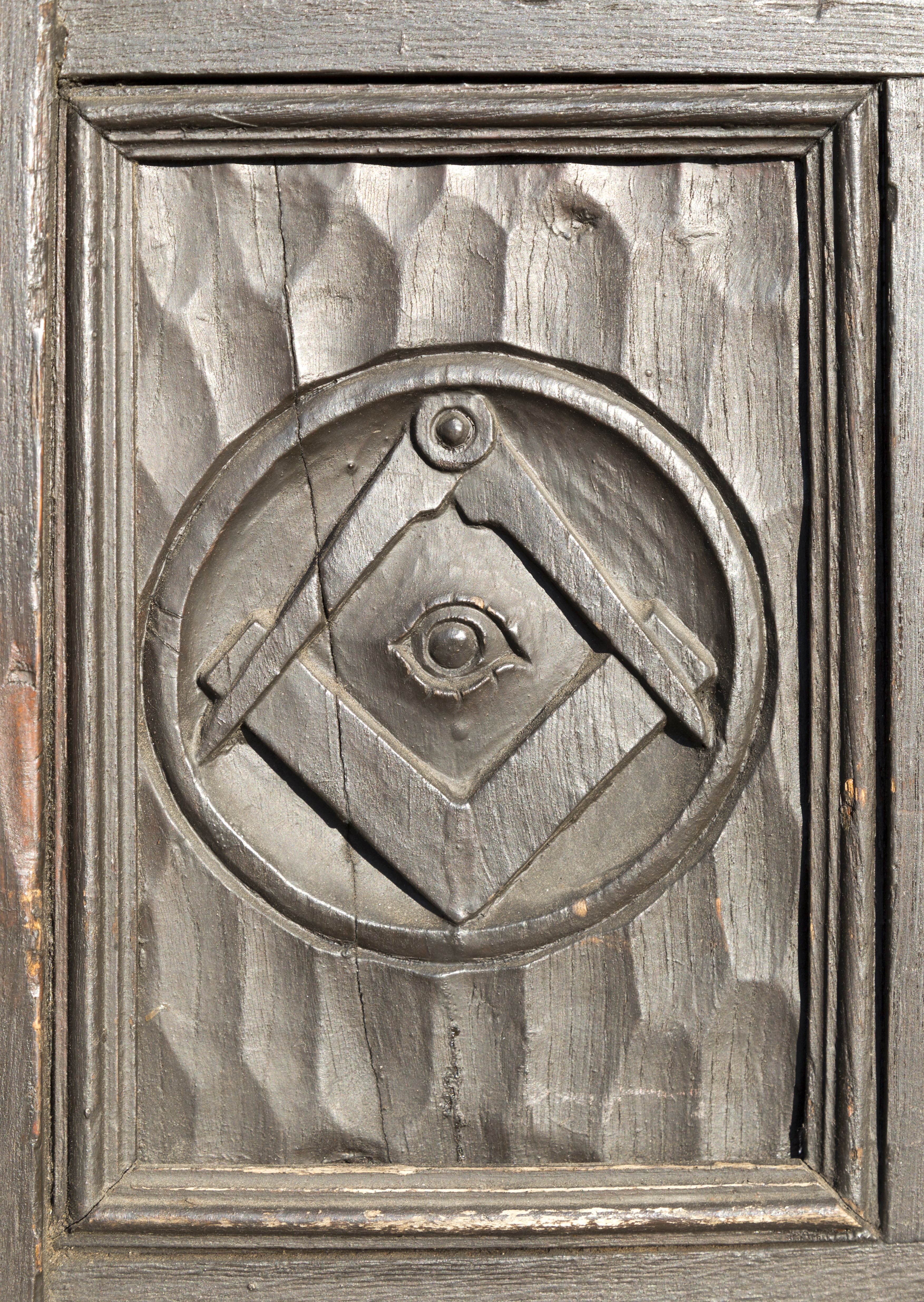 Historic carved masonic symbols on wooden panel on door of house in Marlborough, Wiltshire, England, UK