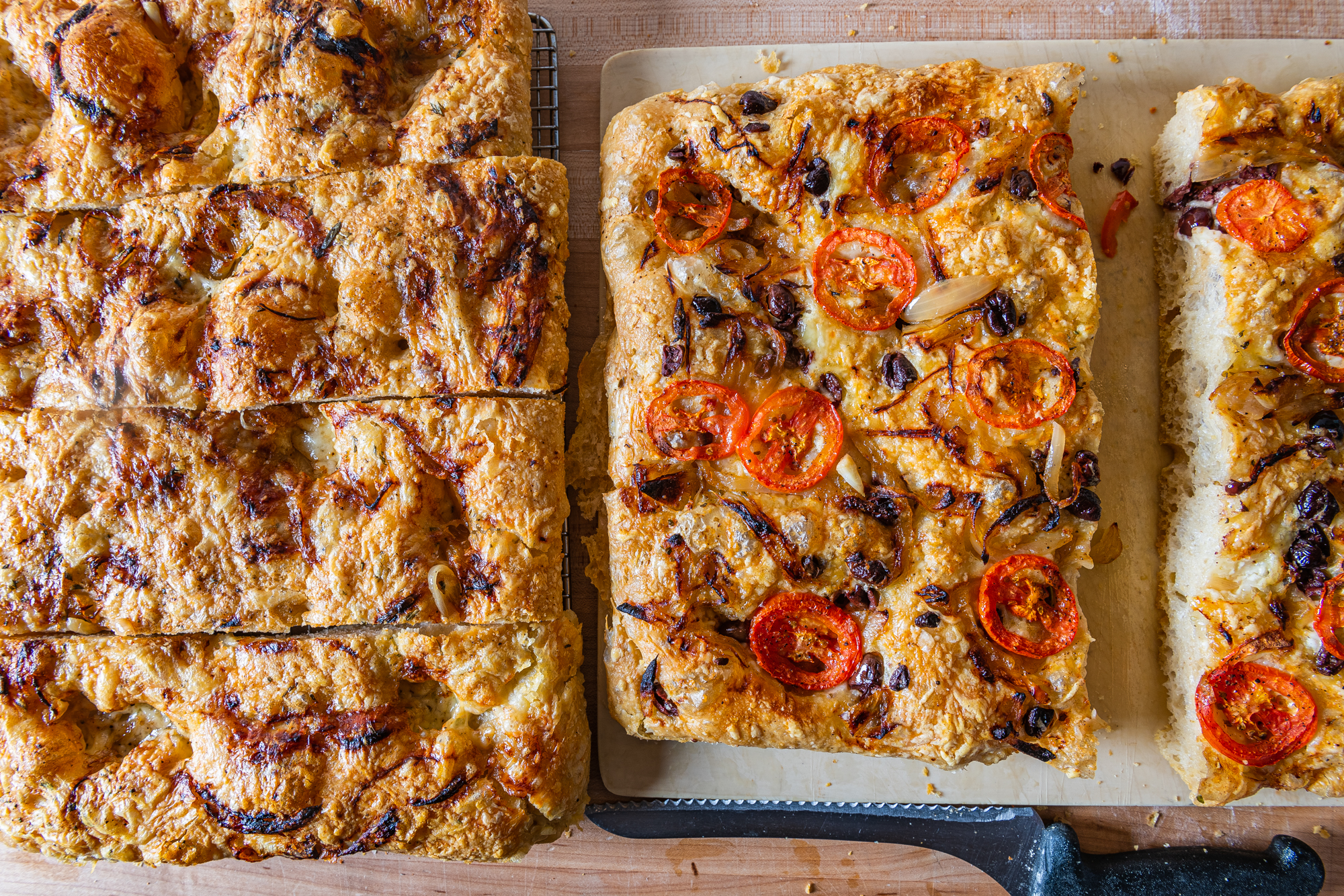 Two sheets of focaccia from Piccolina, covered in tomatoes and onions, respectively
