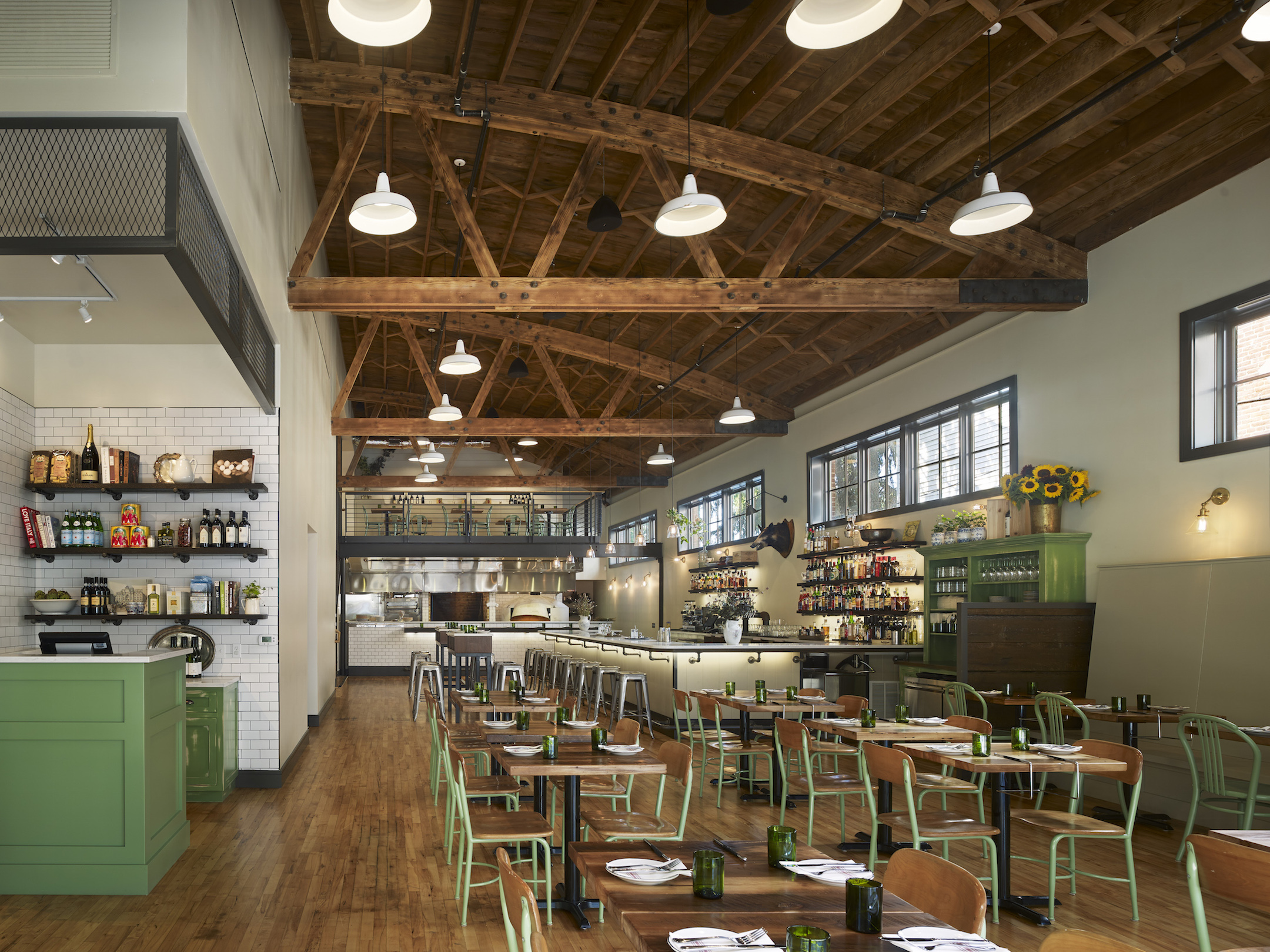 一间带大木制天花板的餐厅，几张桌子和绿色酒吧