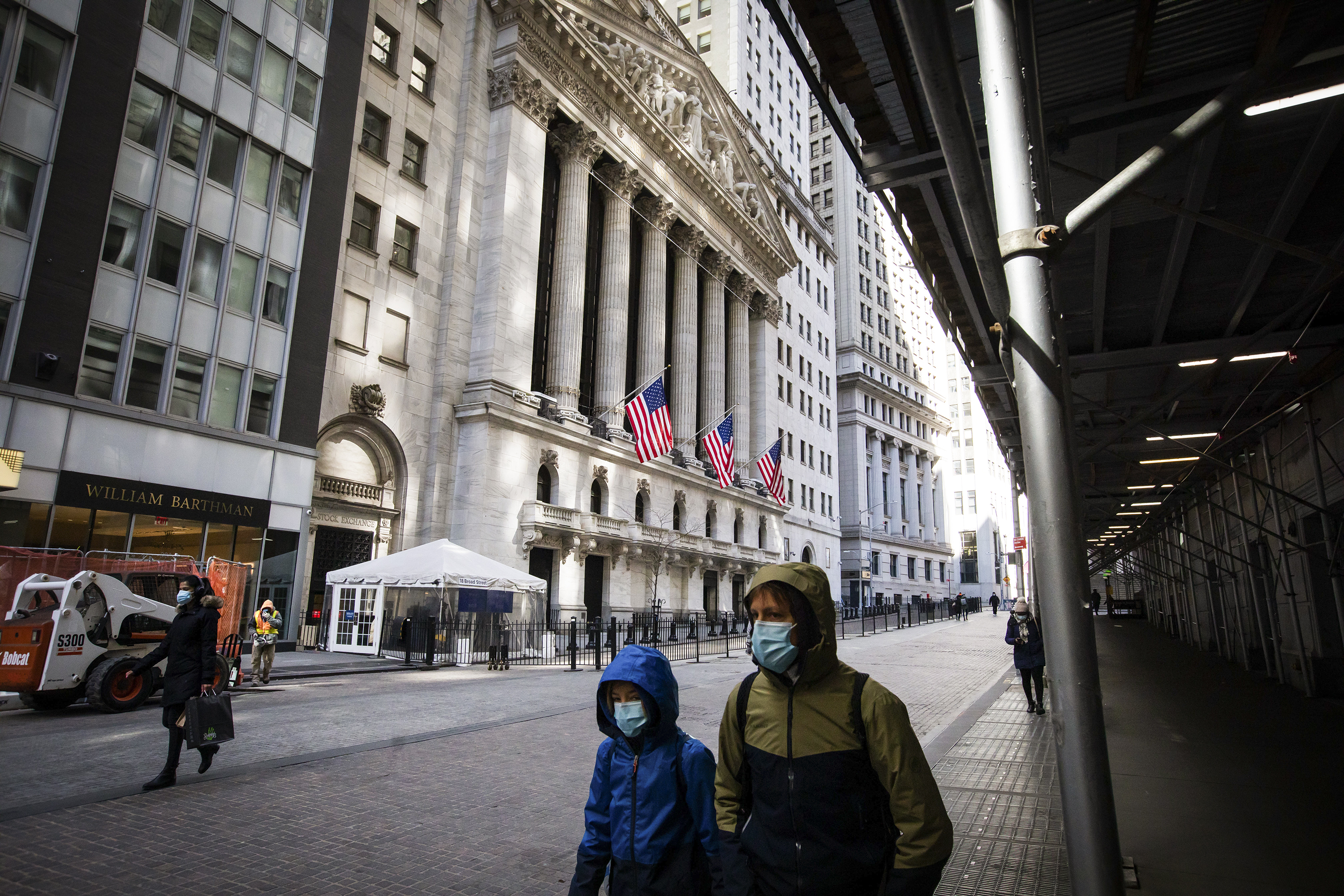A few people walk past the New York Stock Exchange building on Wall Street.