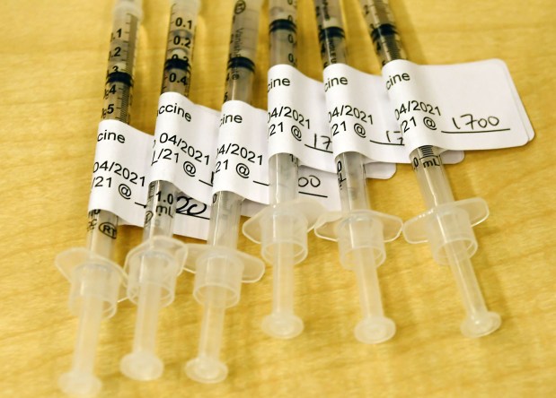 COVID-19 vaccine syringes sit on a table.