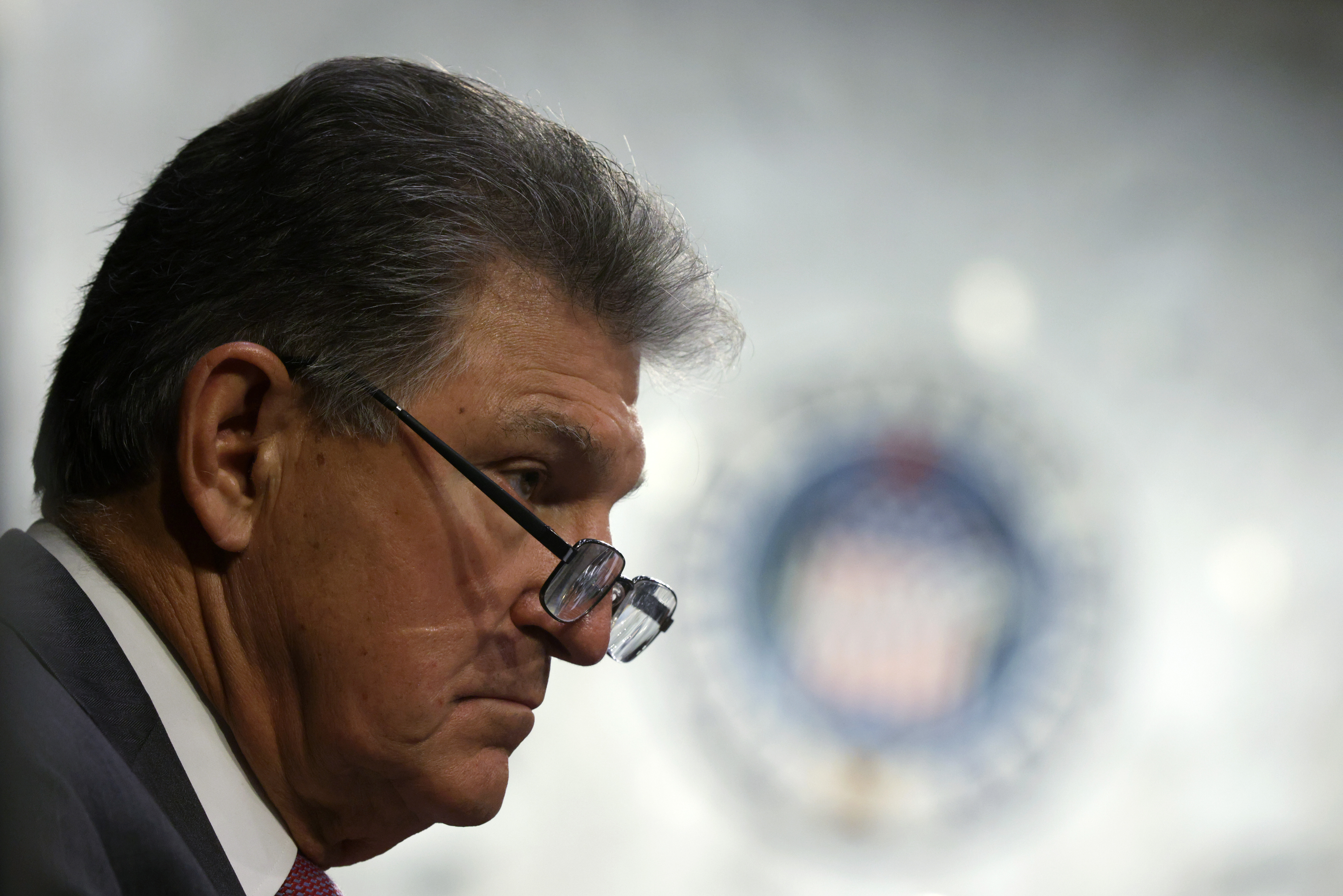 Senator Joe Manchin in profile, with the seal of the Senate on the wall in the background.