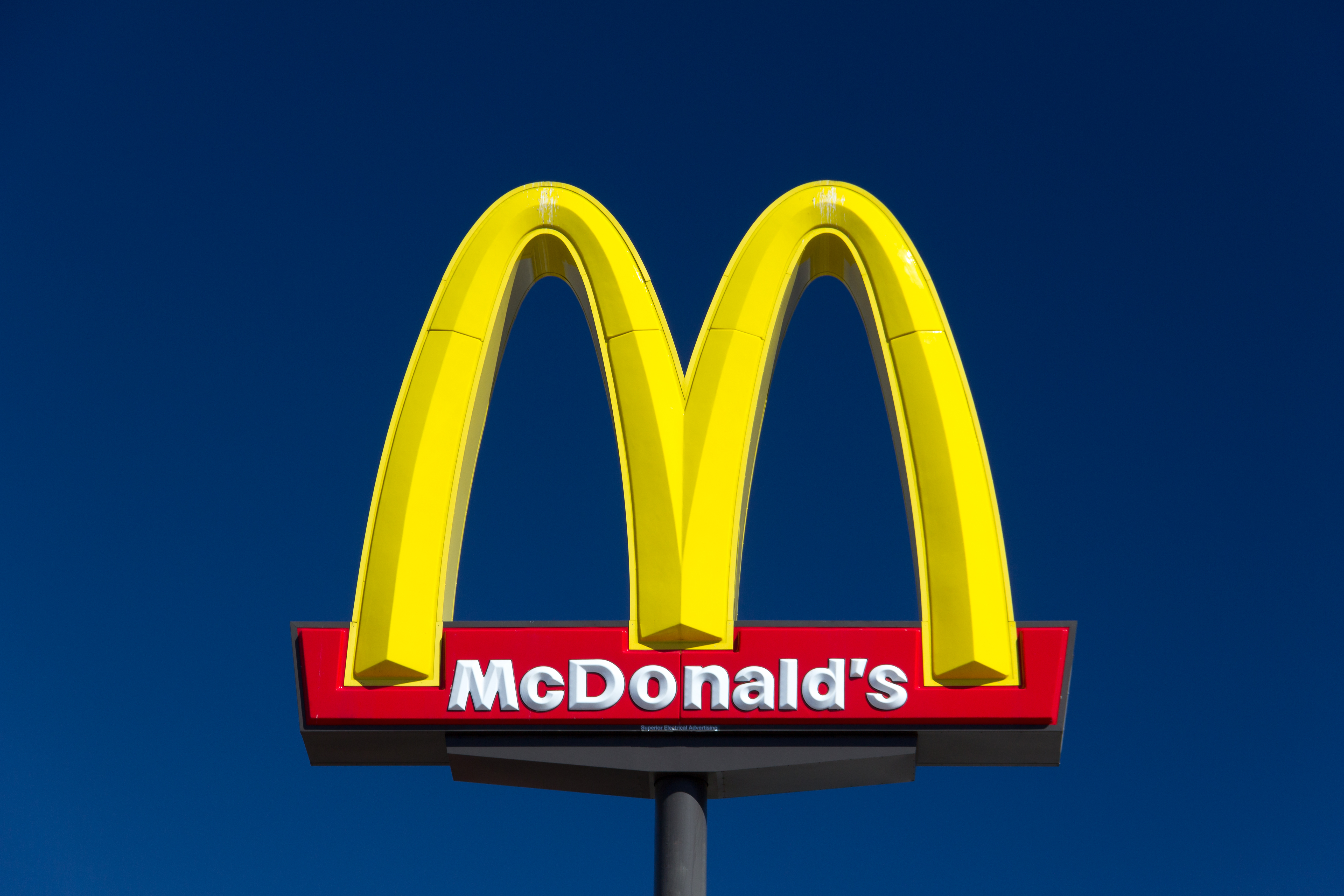 A McDonald’s restaurant sign on a blue sky background.