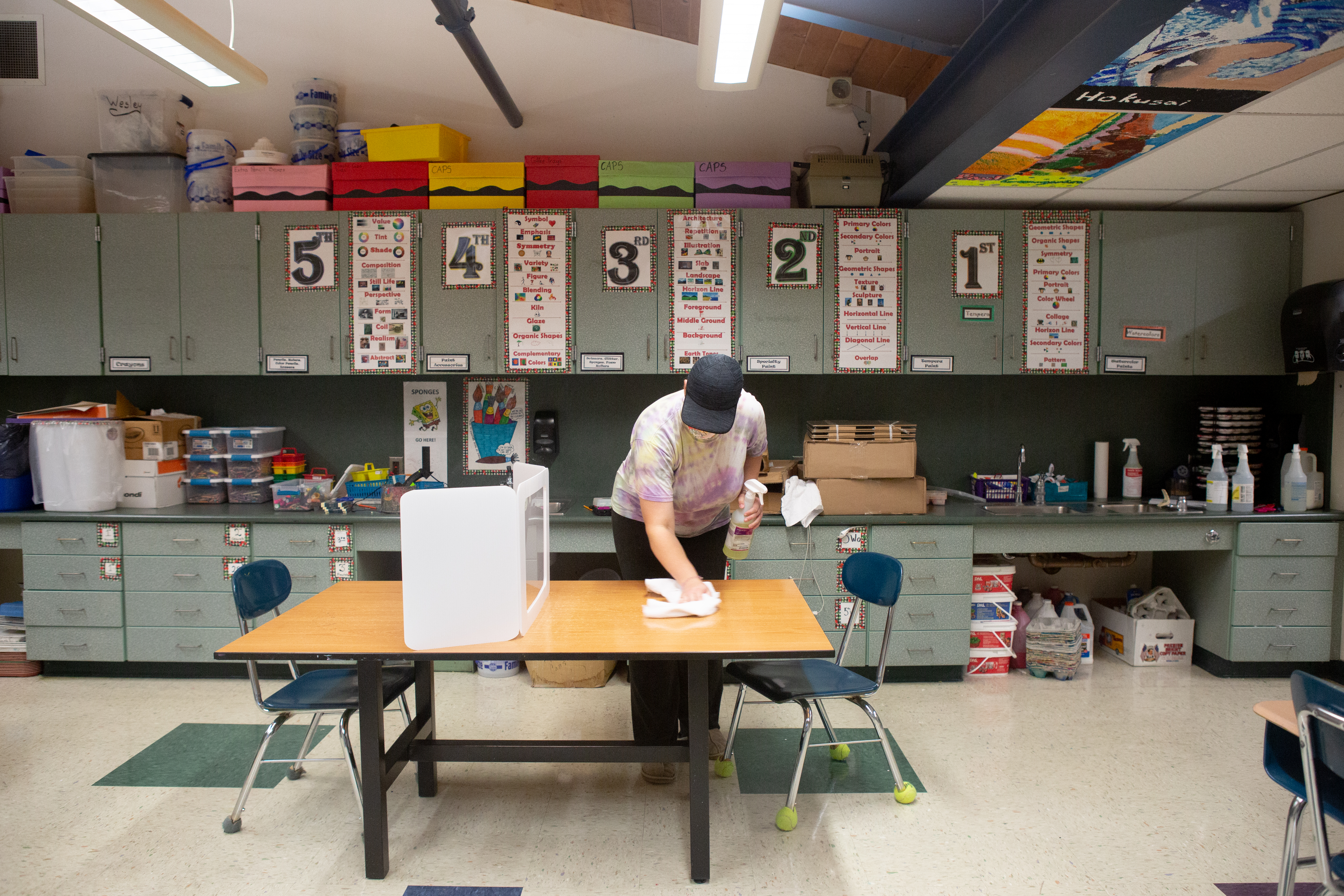 Janitorial staff member Mary Horbock cleans a desk between classes at Wesley Elementary School.