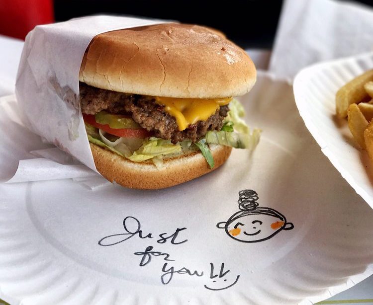 A burger on a plate with a hand-drawn note of thanks.