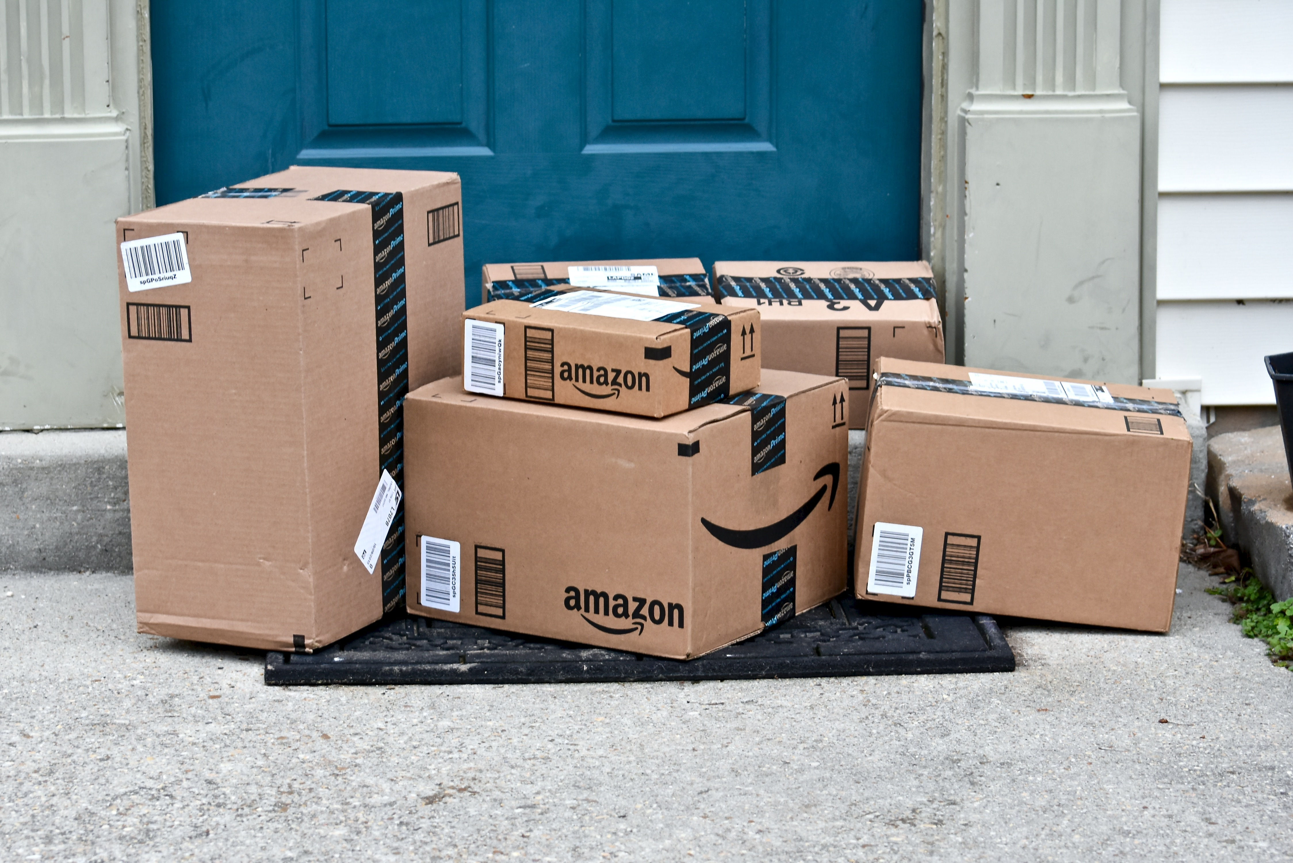 Amazon shipping boxes piled on a doorstep.