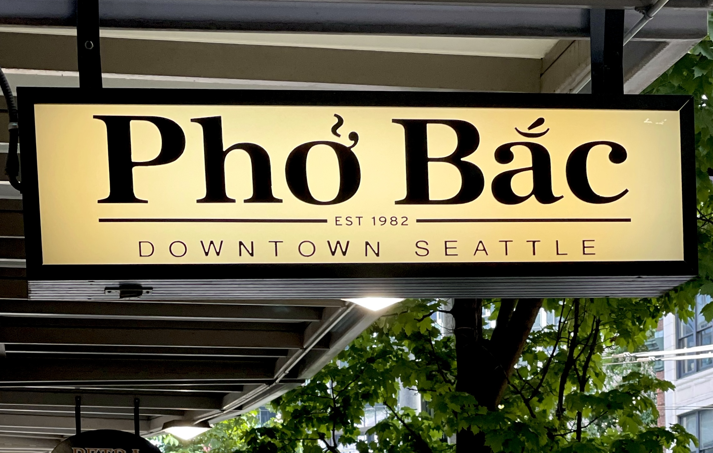 The glowing yellow sign for Pho Bac has the restaurant’s name in bold letters, then below it (smaller) it says EST. 1982, Downtown Seattle.