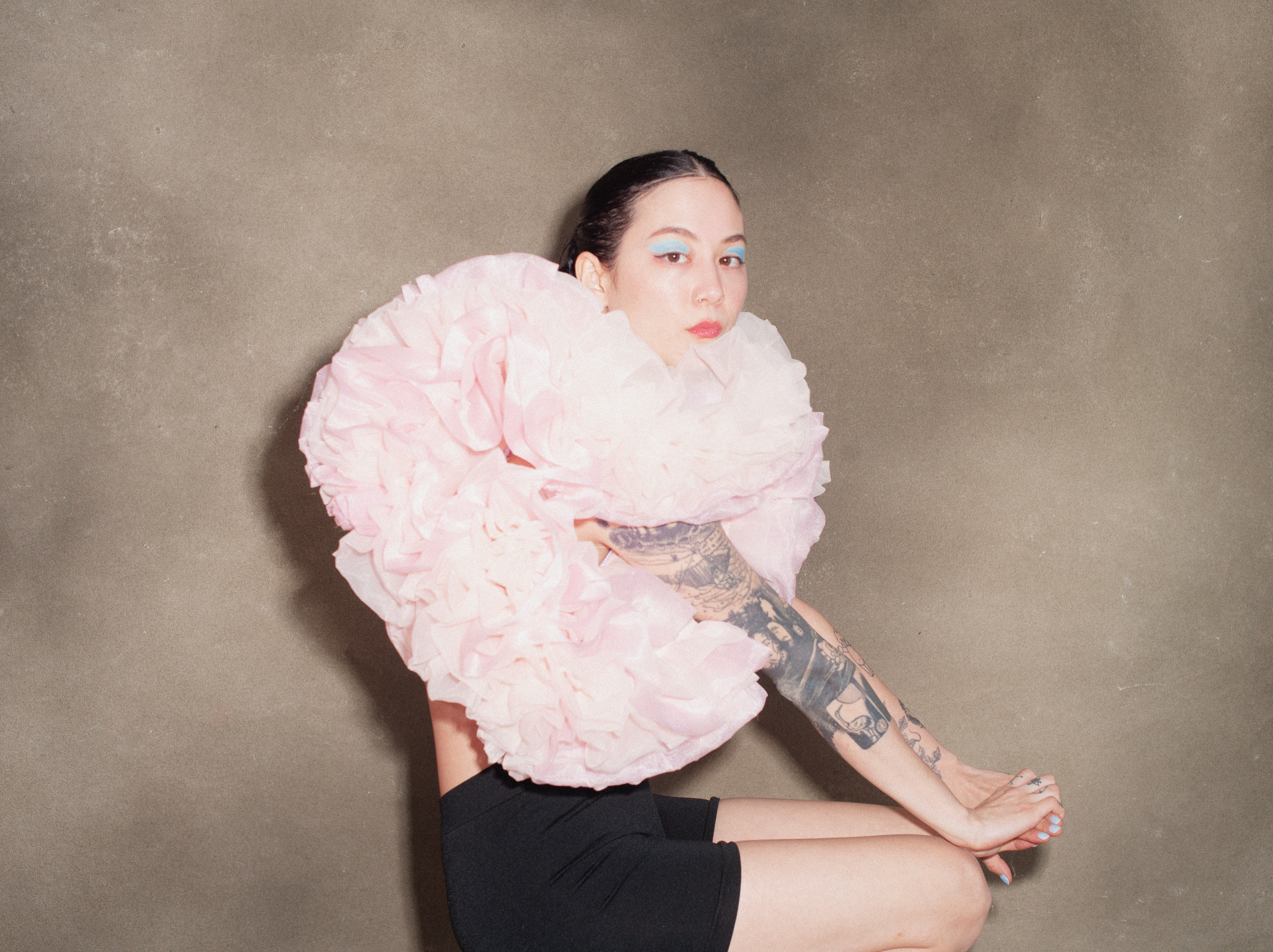 Michelle Zauner, the musical artist known as Japanese Breakfast, sits in a puffy pink top and looks directly at the camera.