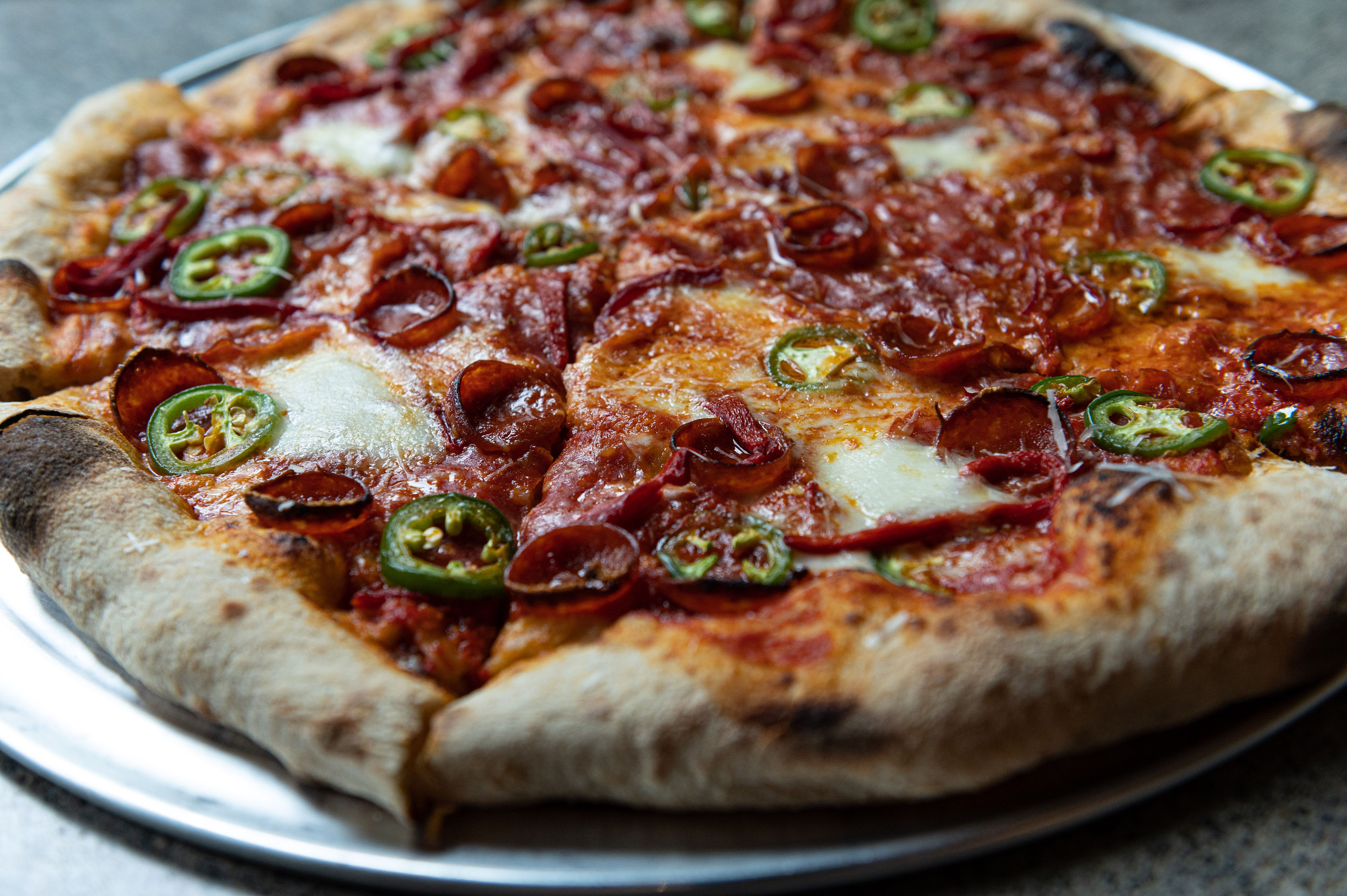 披萨贼店的披萨上有意大利辣香肠和辣椒。