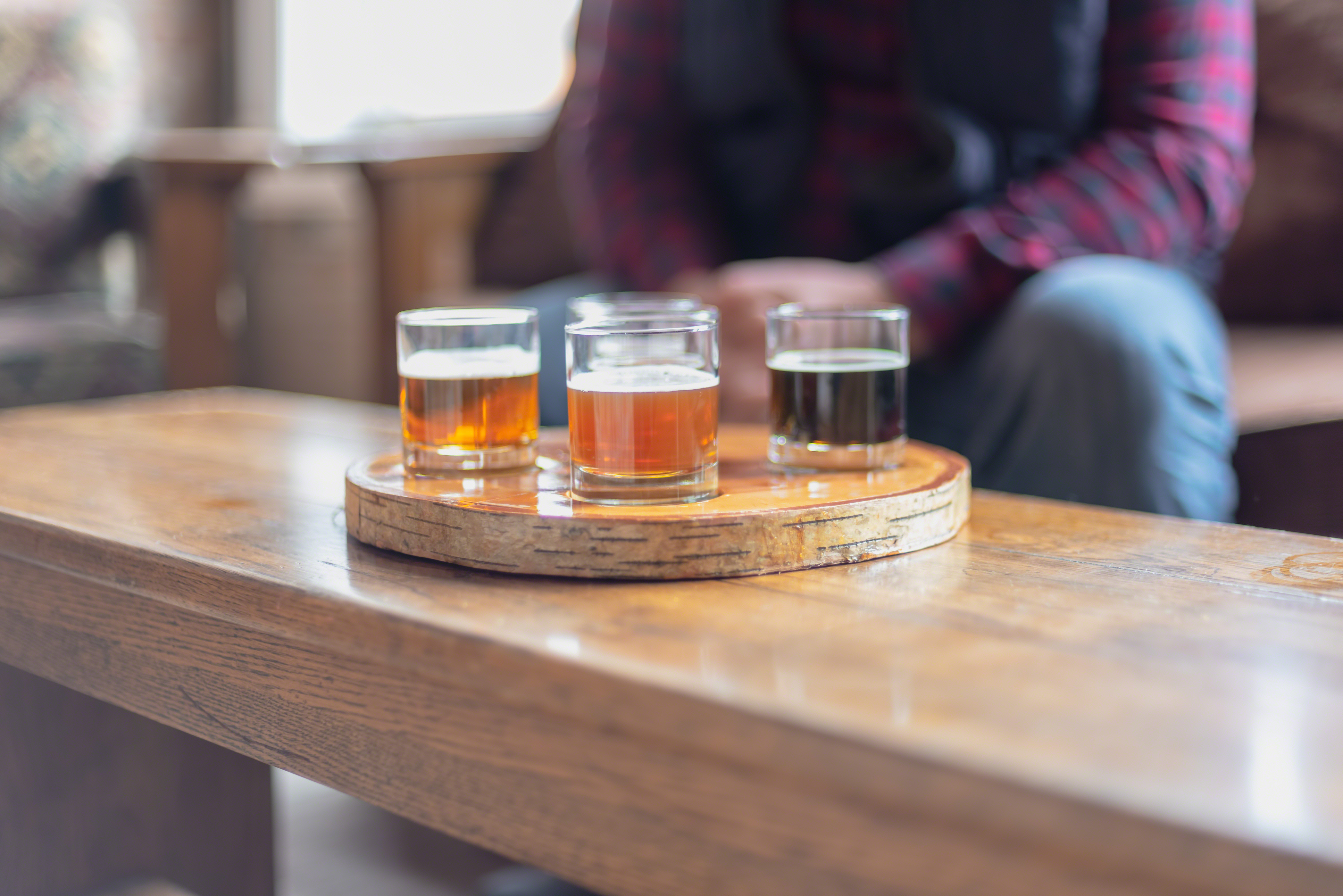 A beer flight in a round wooden carrier on a table.