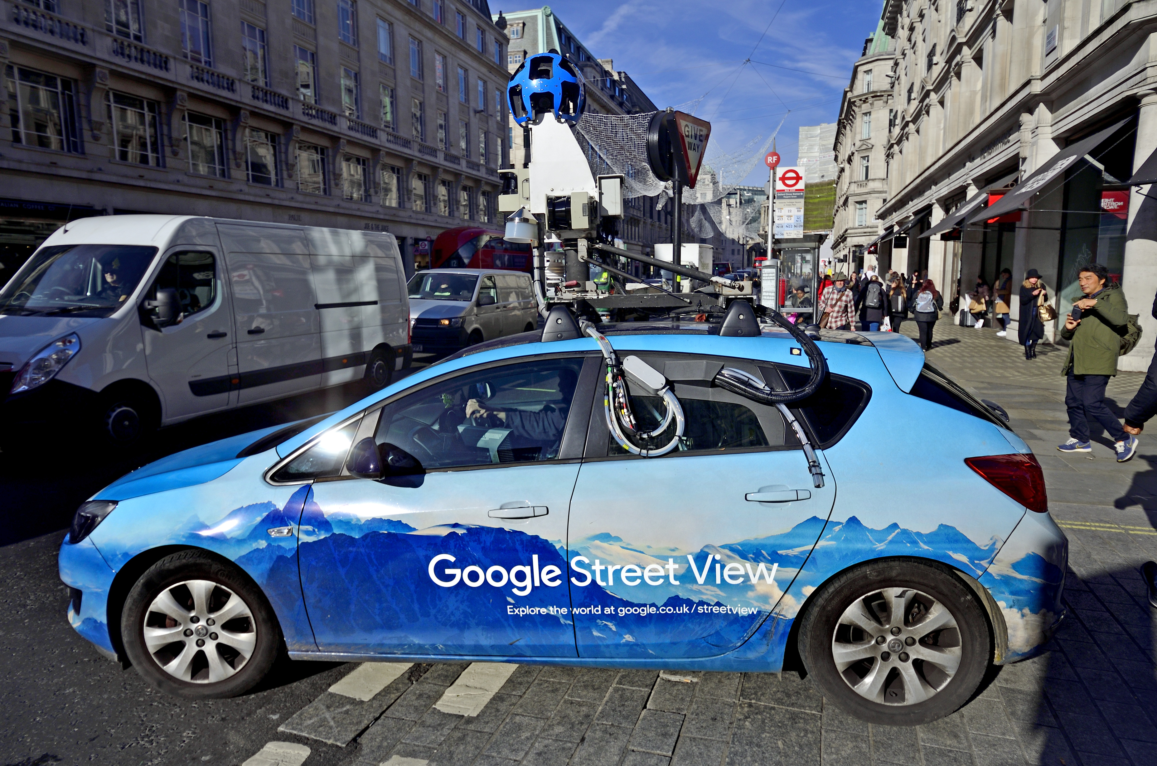 A Google Street View car navigates a crowded street.