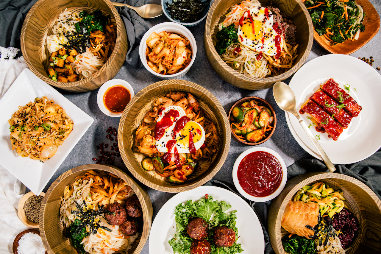 a variety of bowls filled with colorful Korean food on top of griddle 