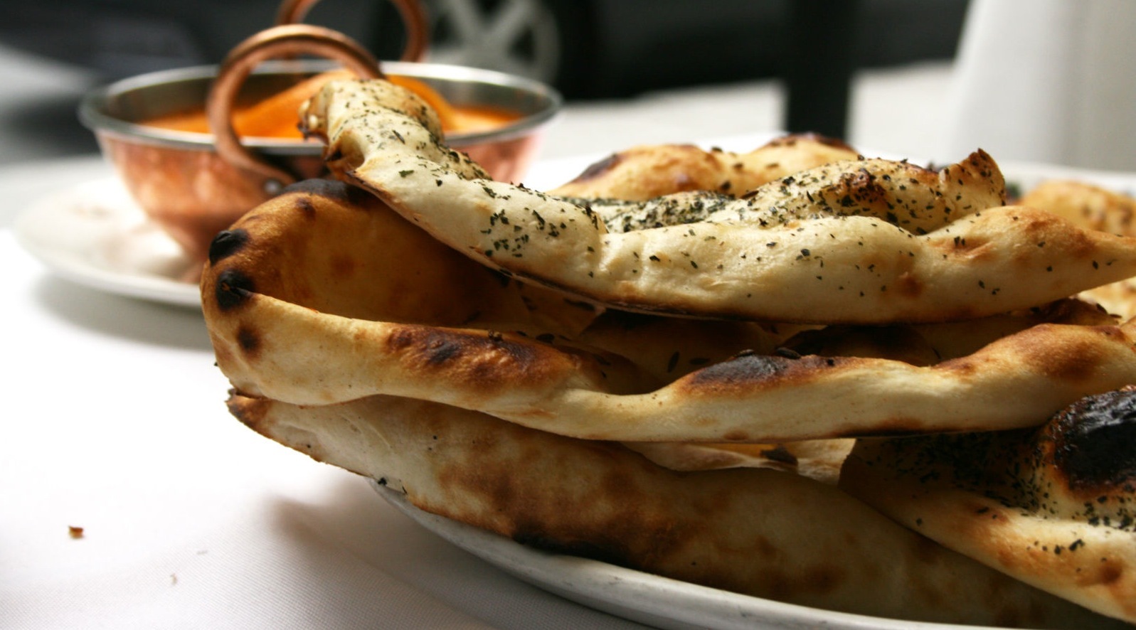 naan with bowl of curry in the background