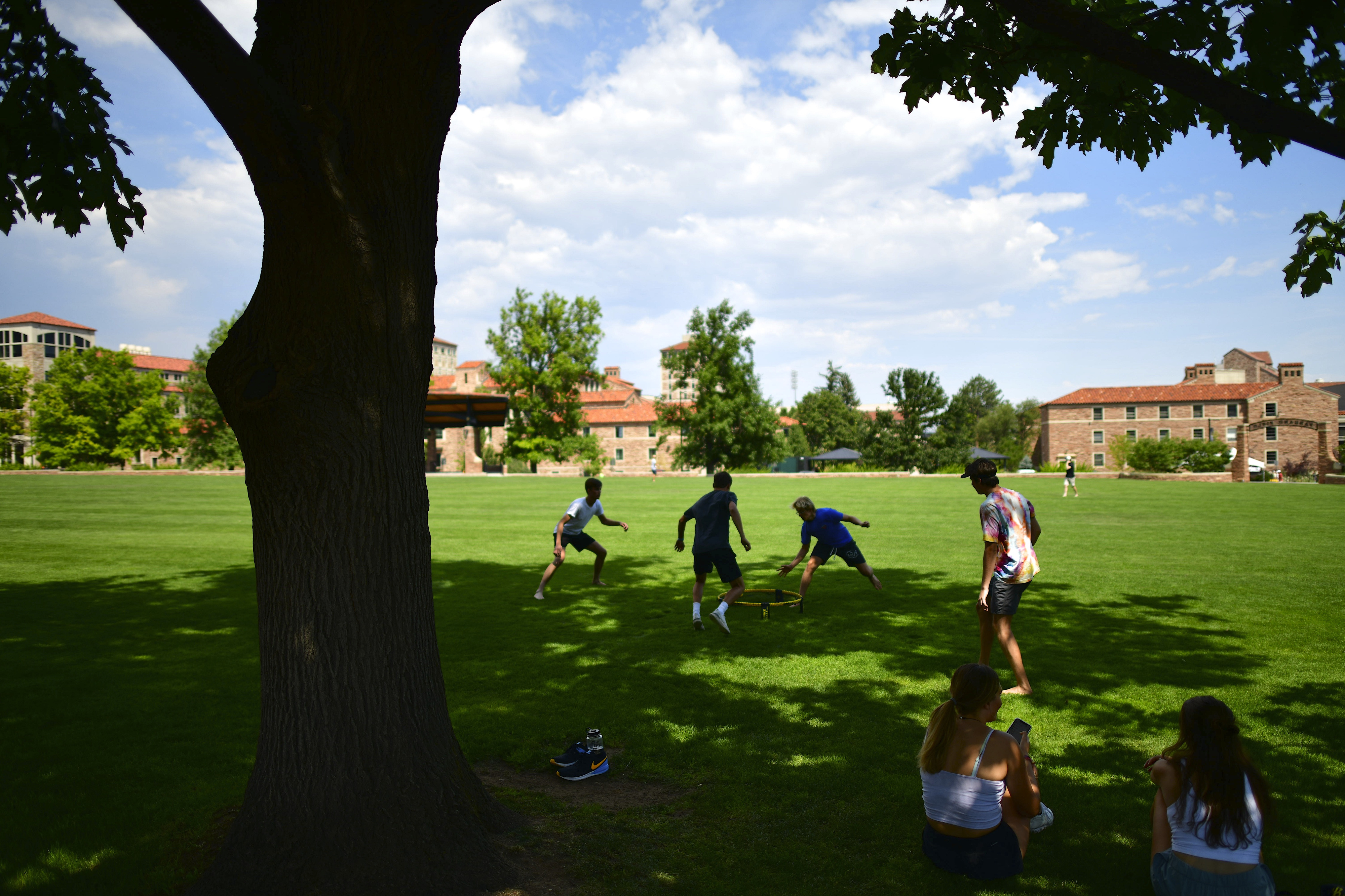 Students play on the lawn at the University of Colorado at Boulder campus on a bright sunny day.
