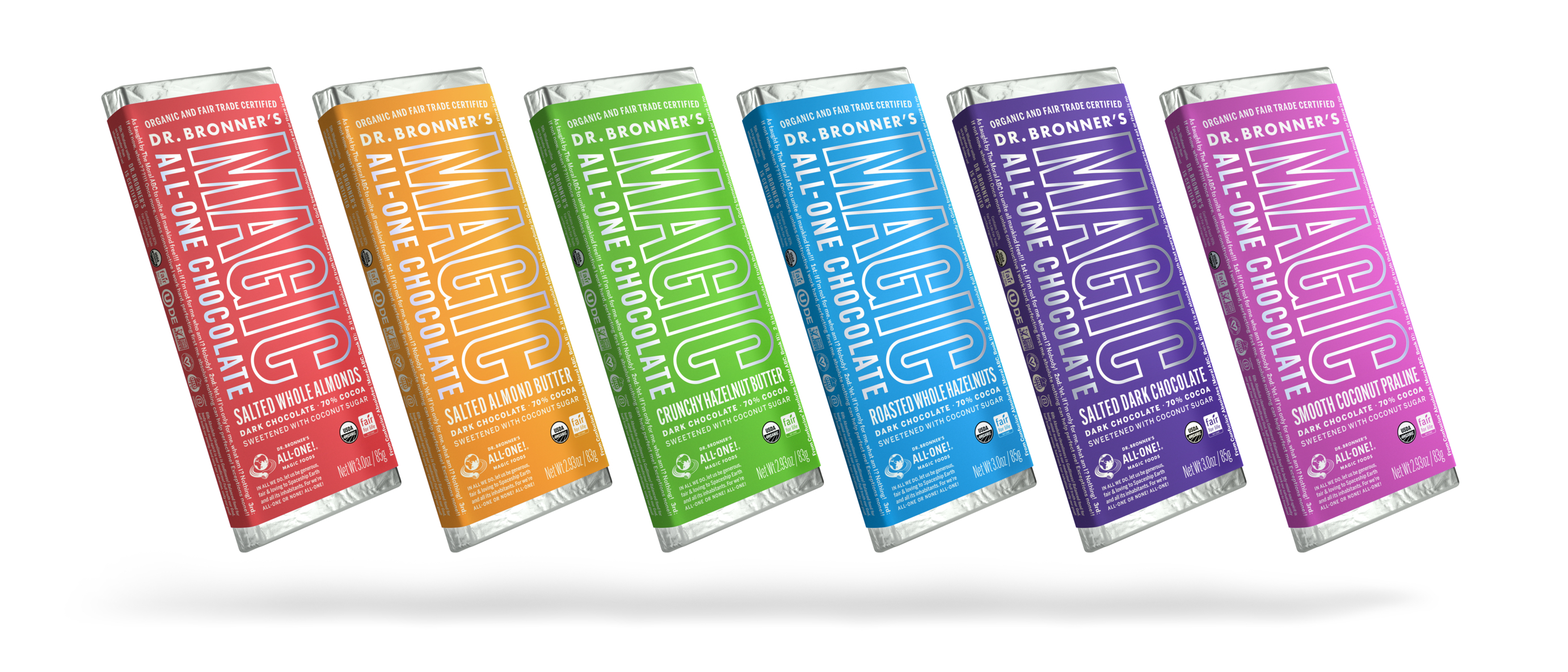 Four bars of Dr. Bronner’s chocolate wrapped in a variety of brightly colored paper (yellow, green, blue, and purple), photographed against a white studio background.